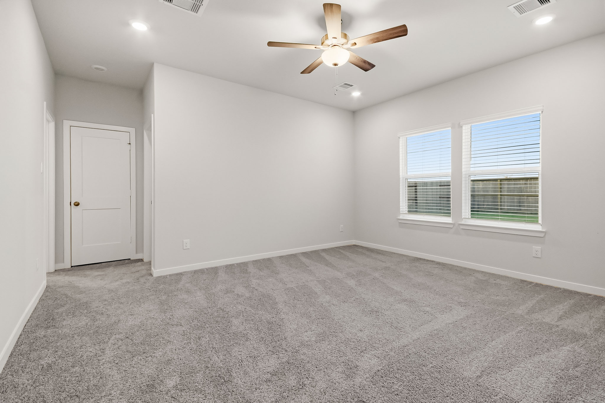 A room with a ceiling fan and a door.