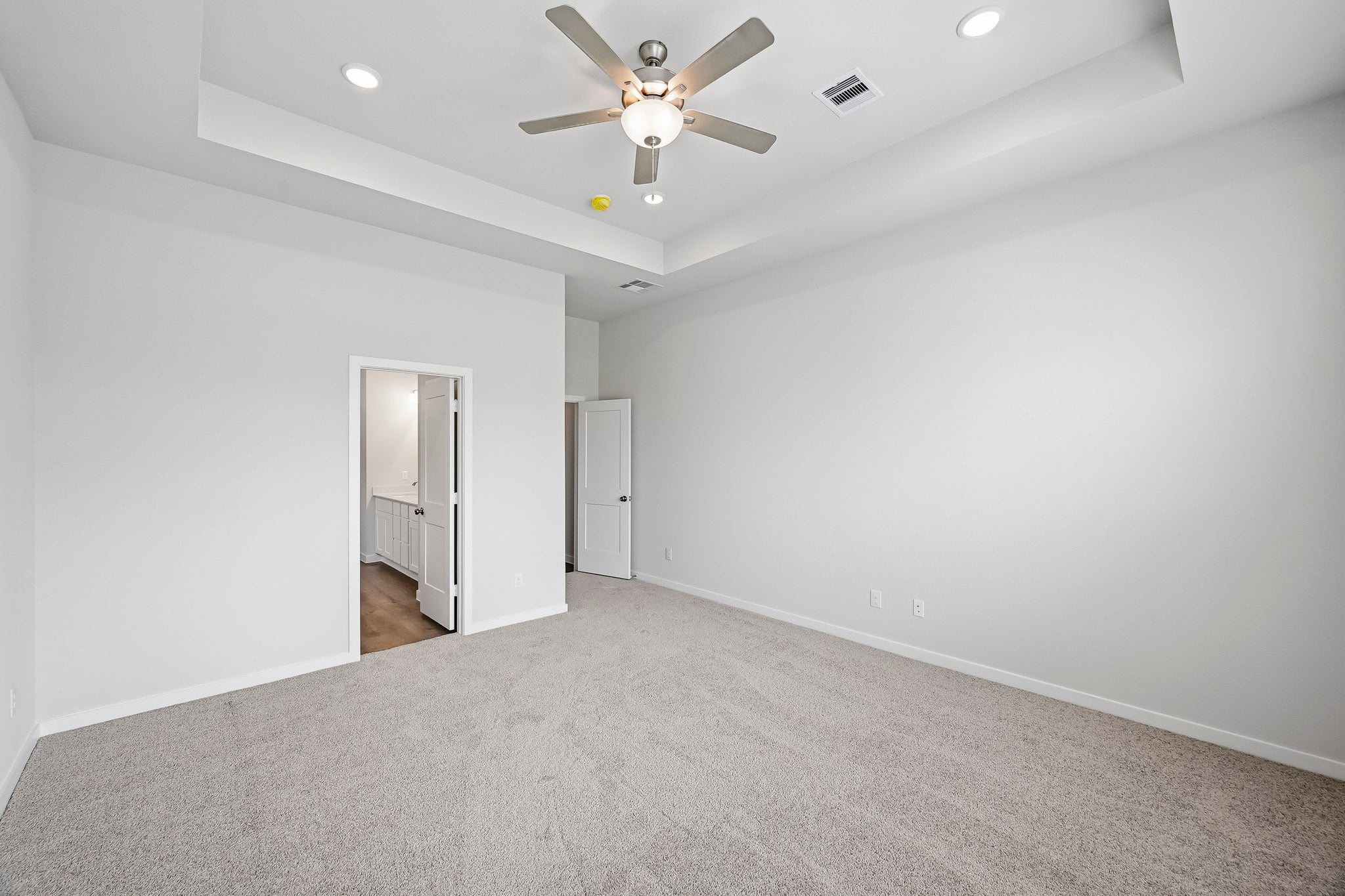 A room with a ceiling fan and a carpet.