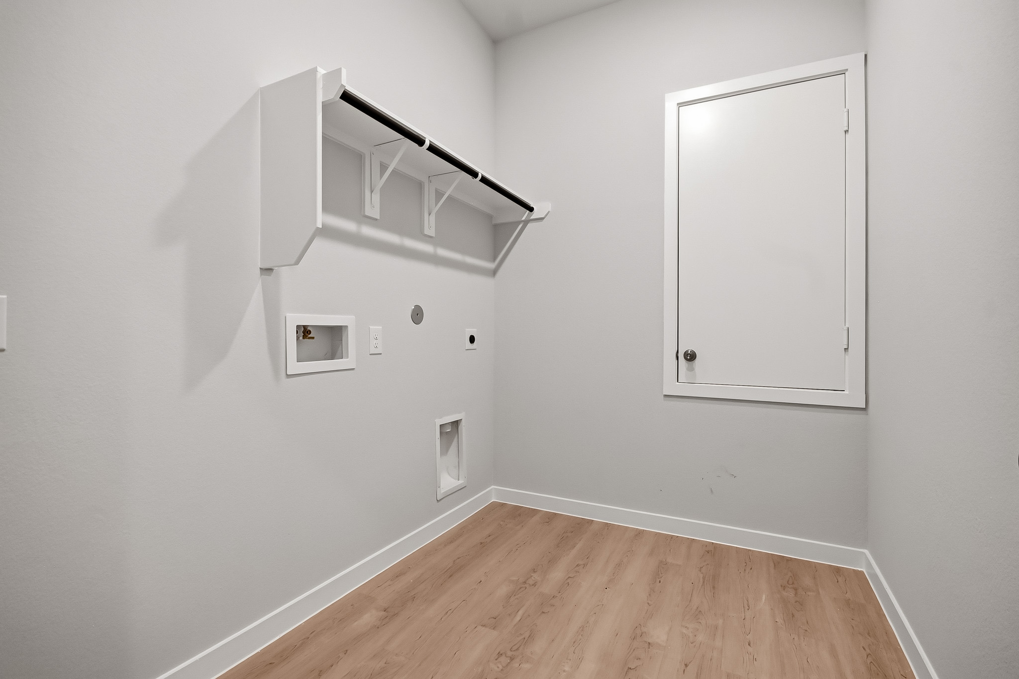 A white room with a wood floor and white walls.