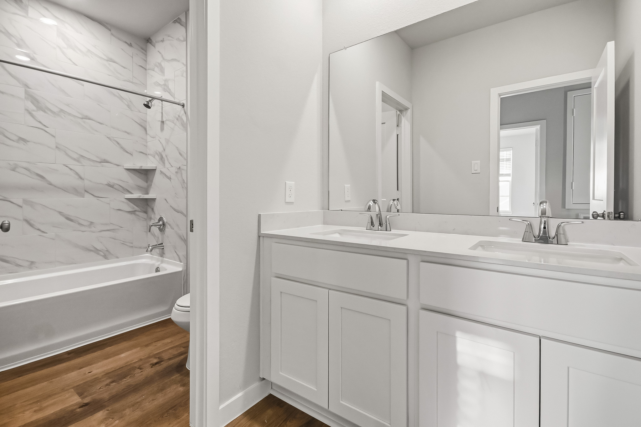 A bathroom with a tub sink and mirror.