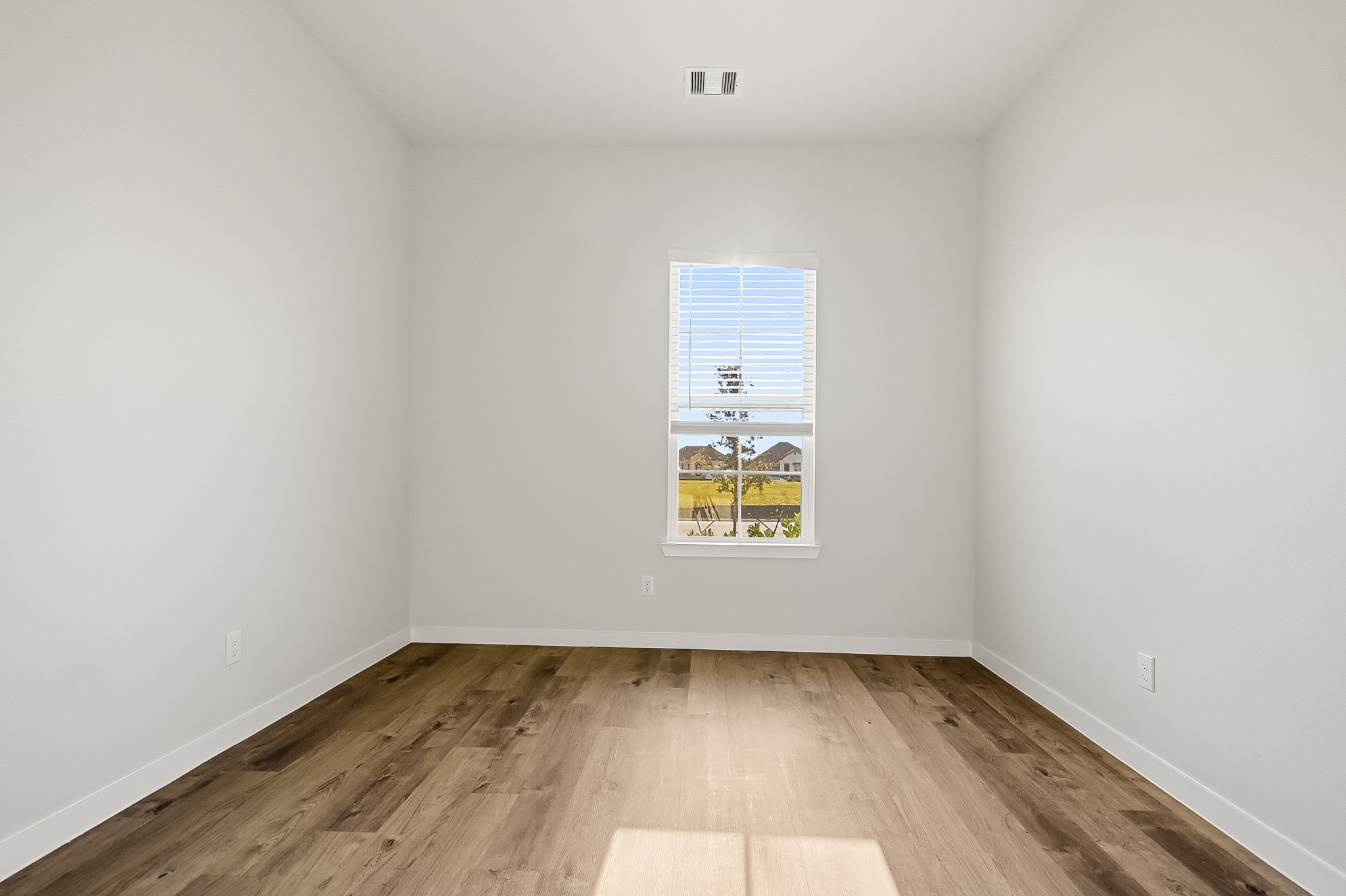 A room with a wood floor and a window with a sign on it.