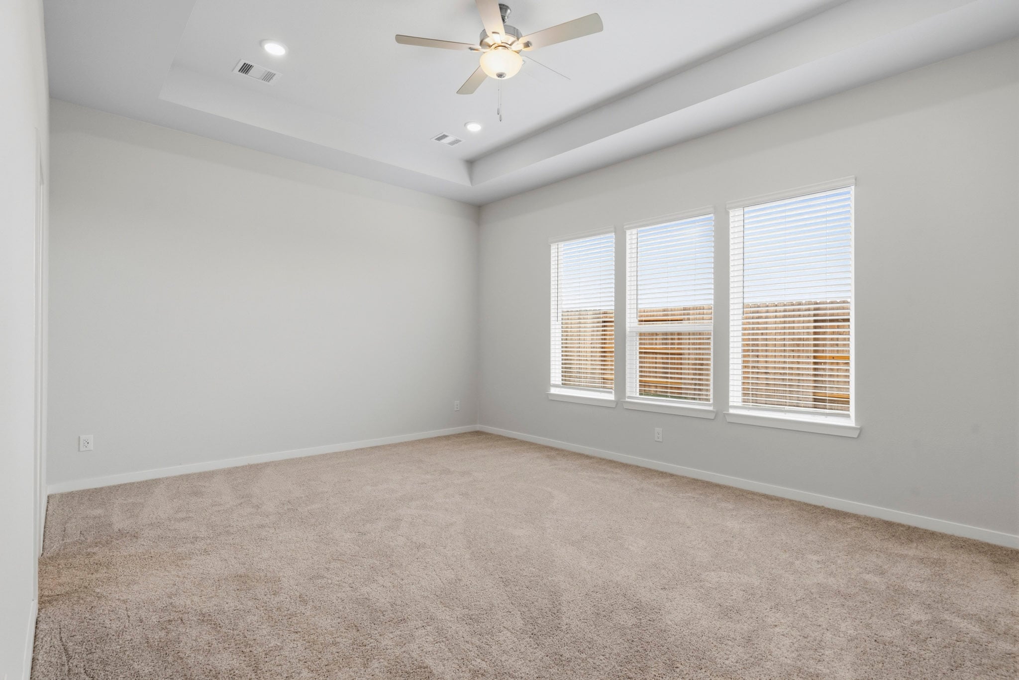 A room with a ceiling fan and a carpet.