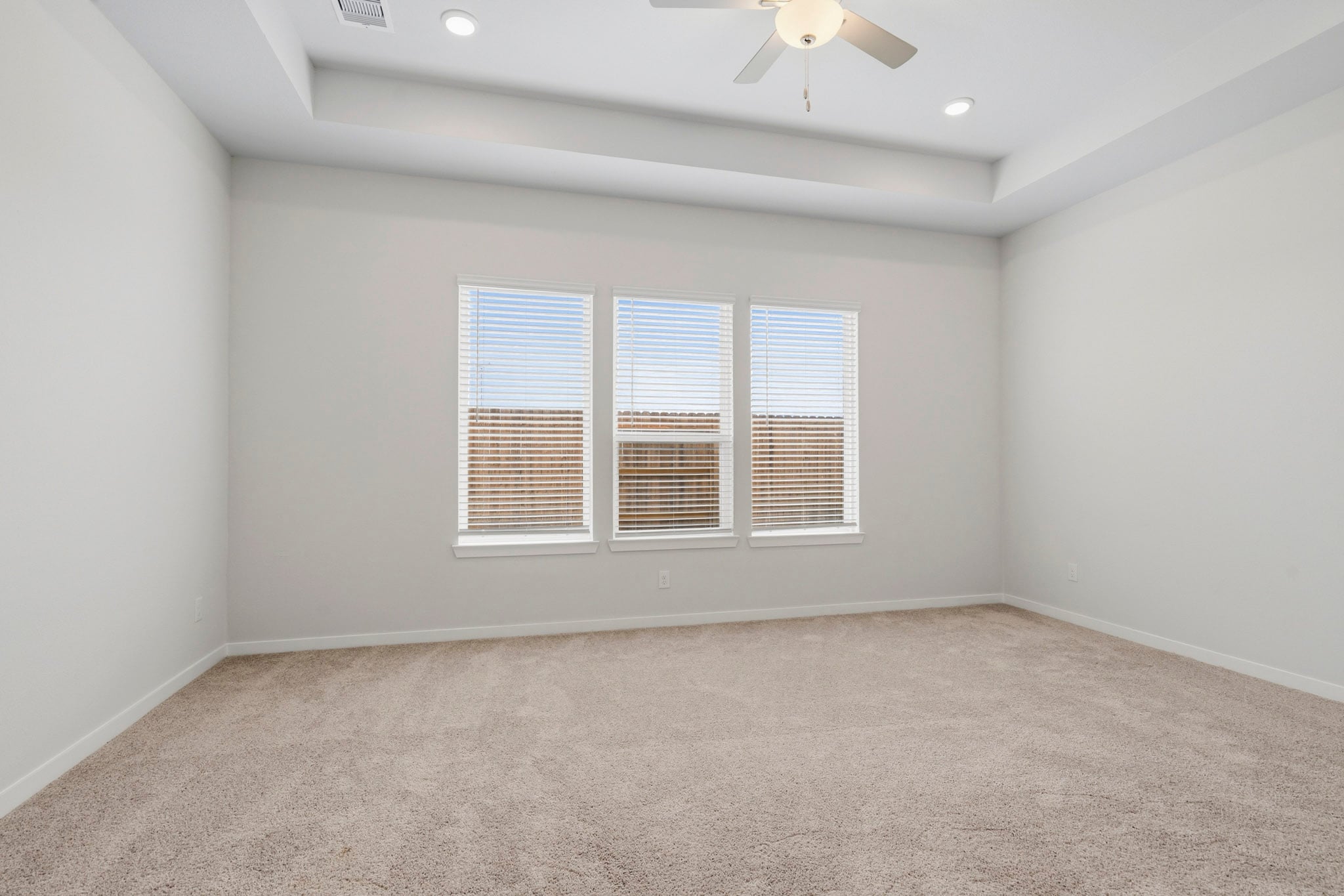 A room with a ceiling fan and a carpet.