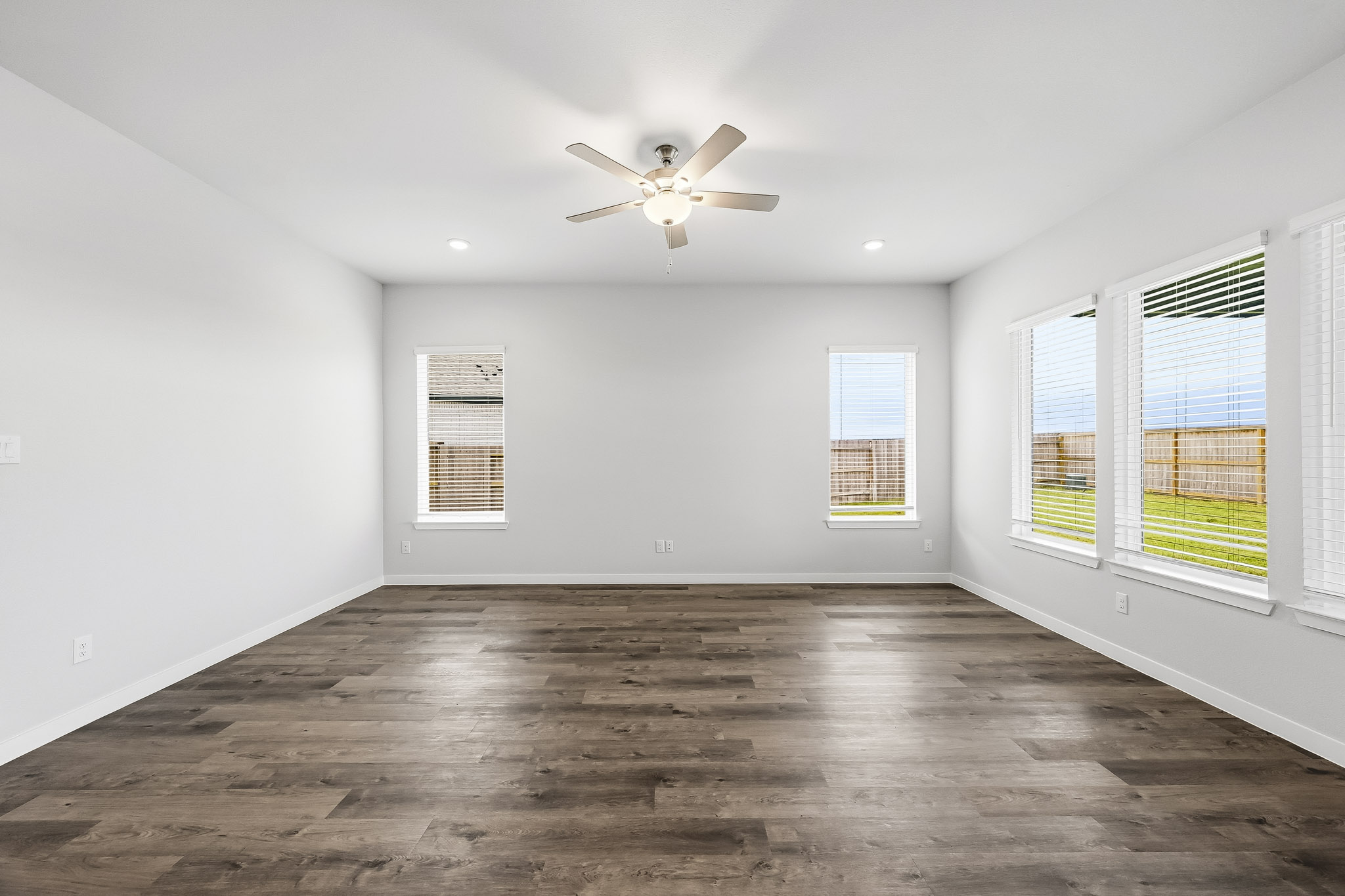 A room with a ceiling fan and windows.