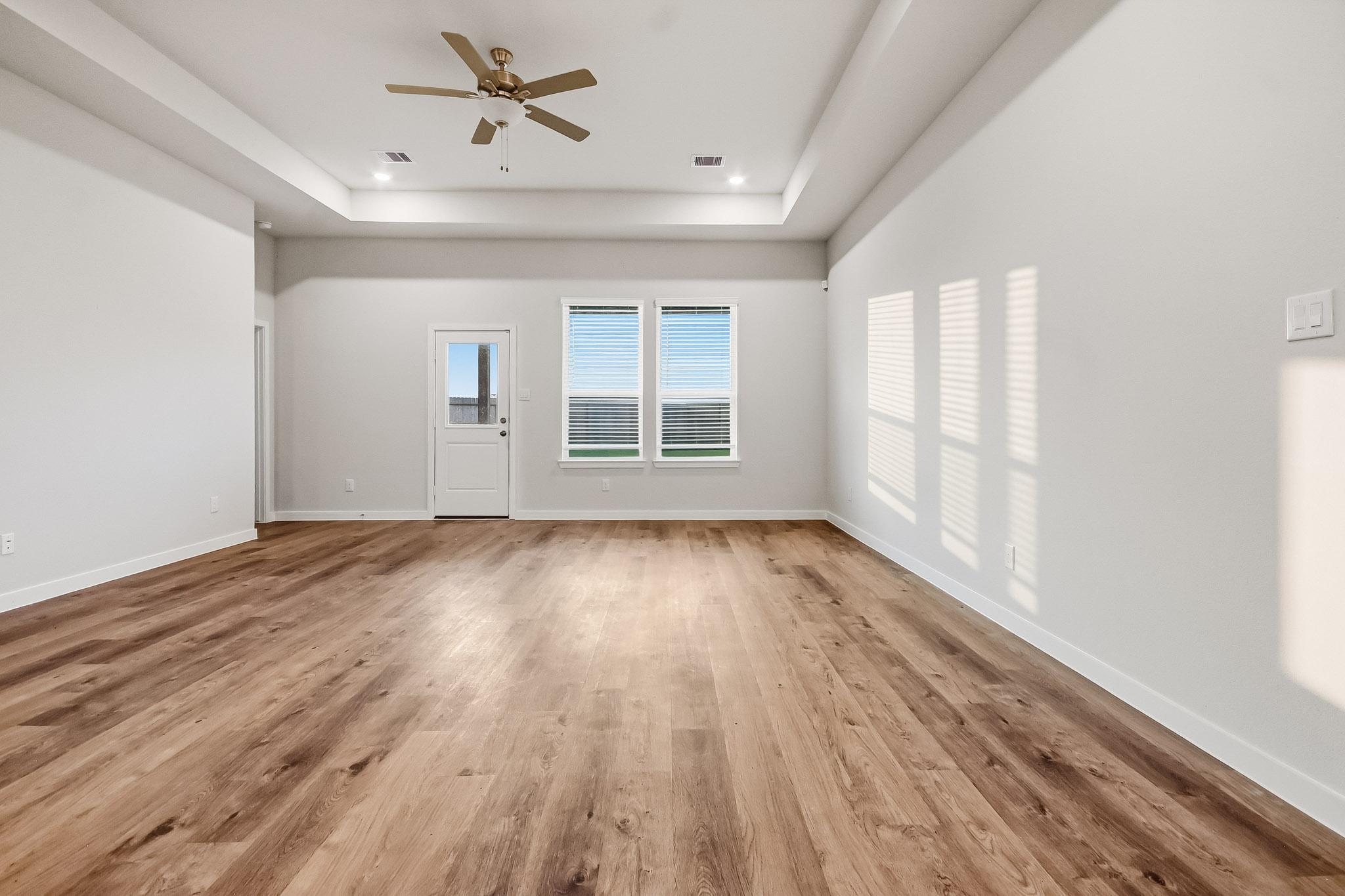A room with a wood floor and a ceiling fan.