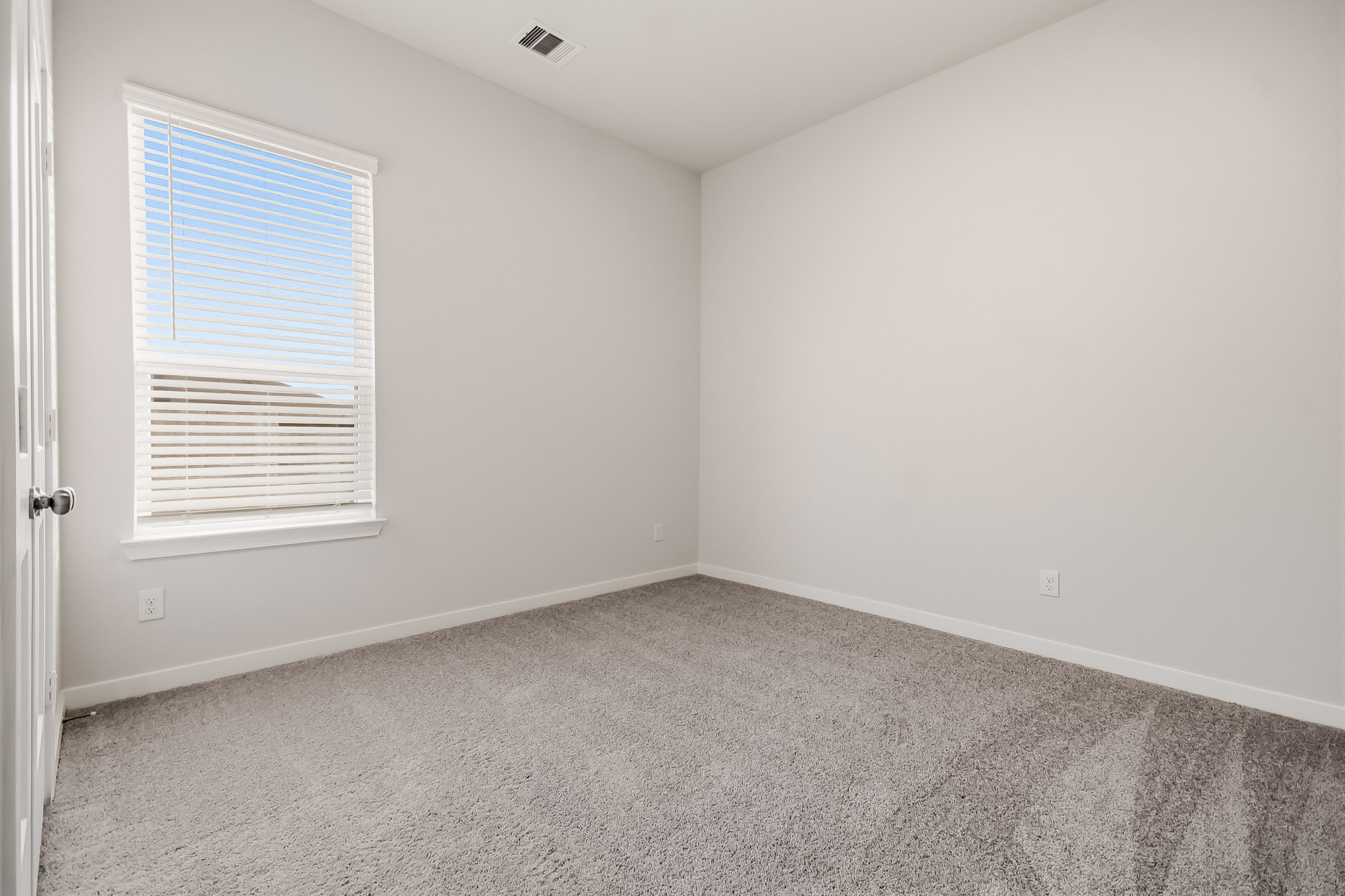 A room with a carpet and a window.