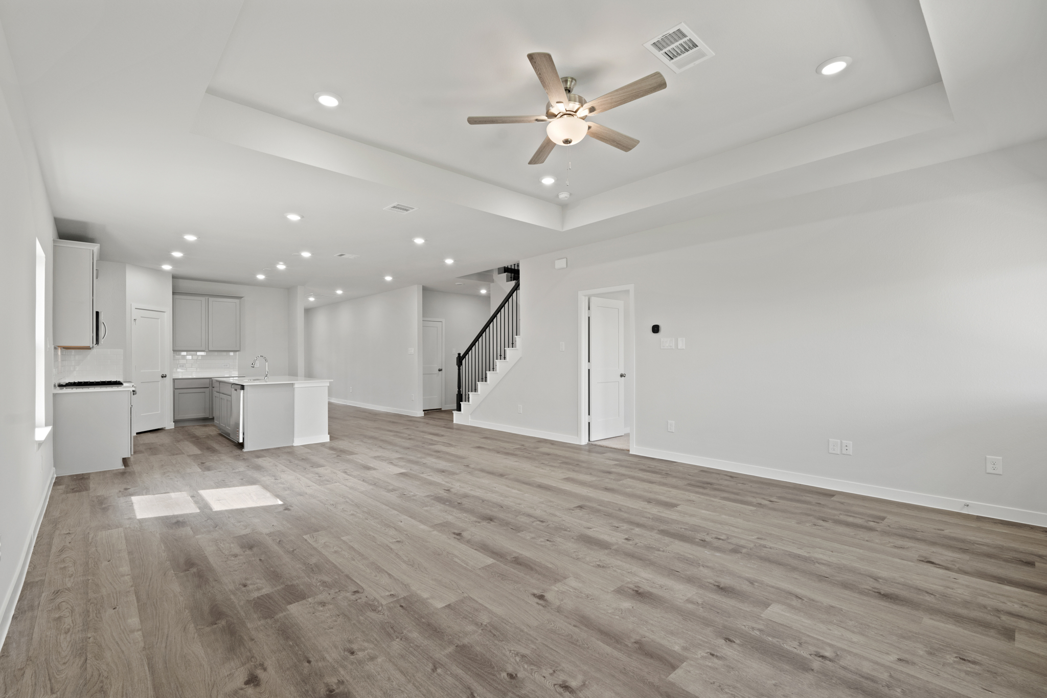 A large empty room with a wood floor and a ceiling fan.