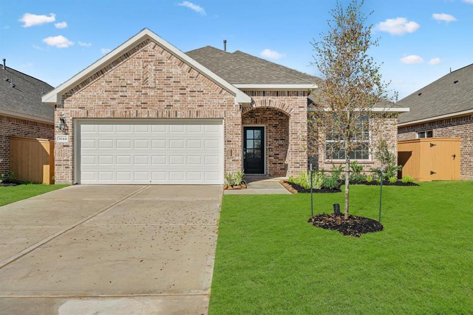 A house with a garage and a tree in the front.