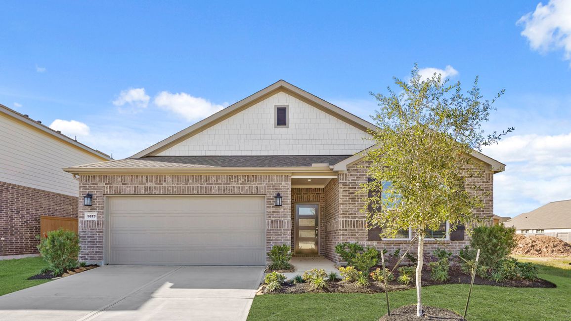 A house with a garage and a tree in the front.