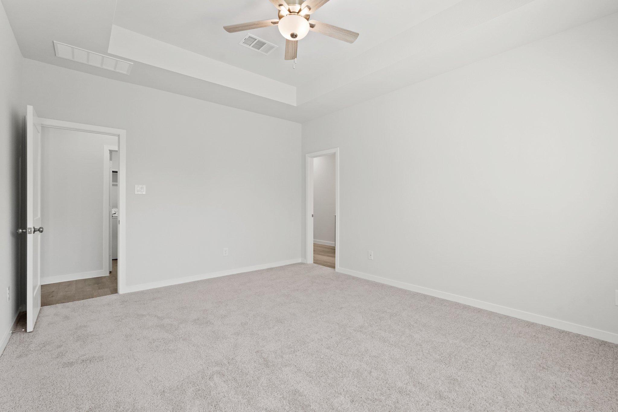 A room with a ceiling fan and a door.