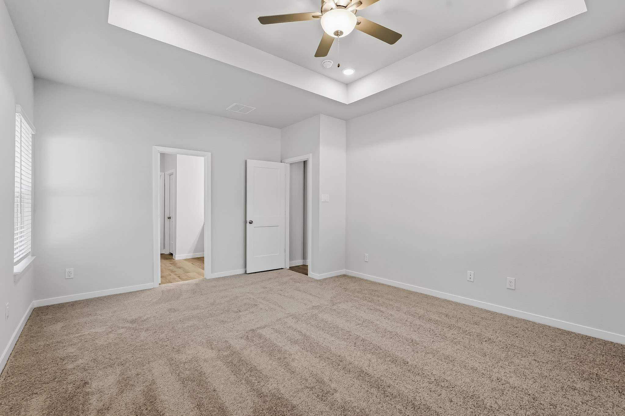 A room with a ceiling fan and a carpet.