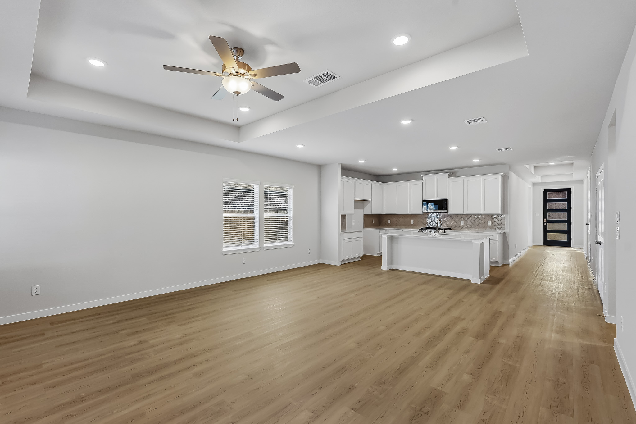 A large empty room with a wood floor and a ceiling fan.