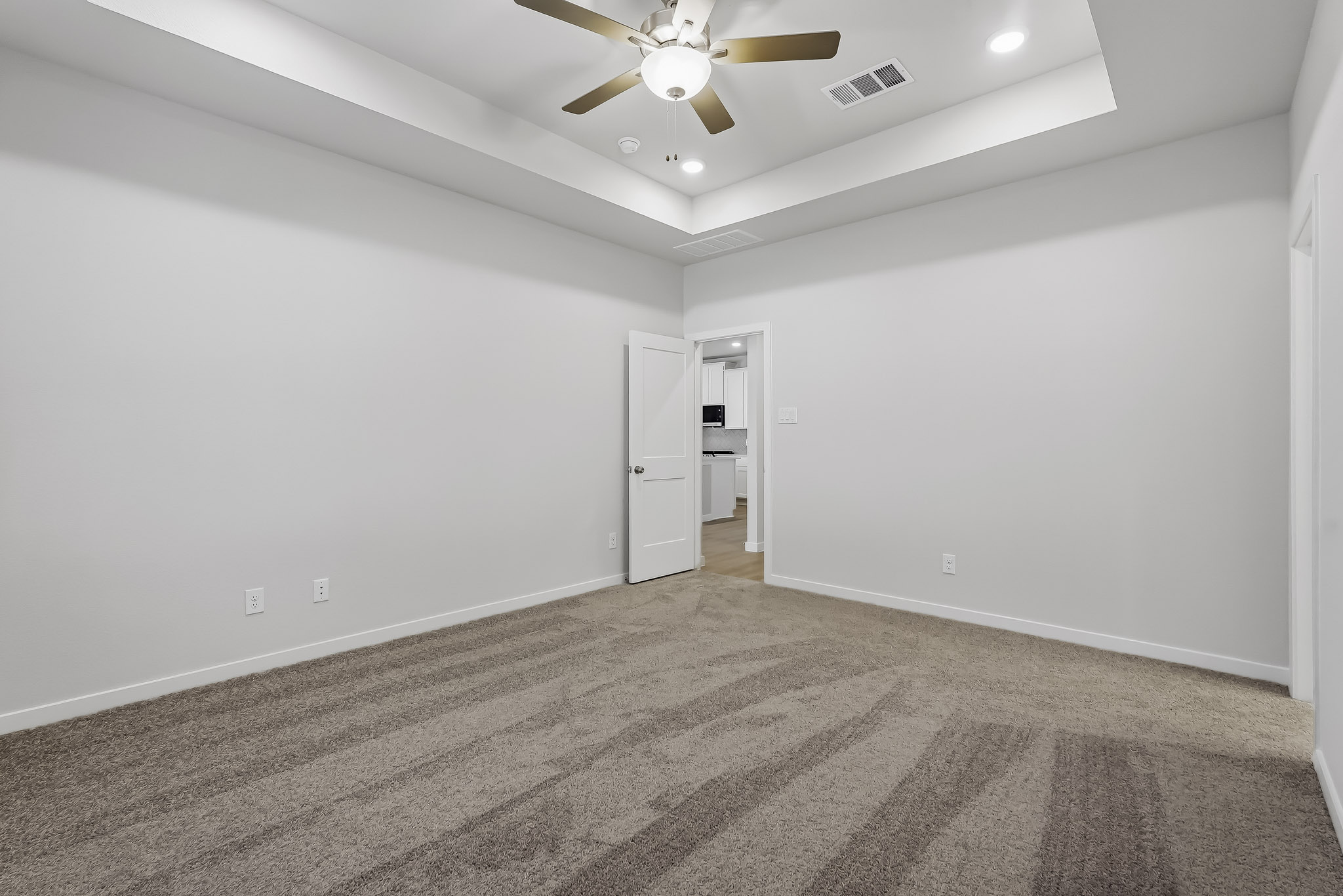 A room with a ceiling fan and a door.