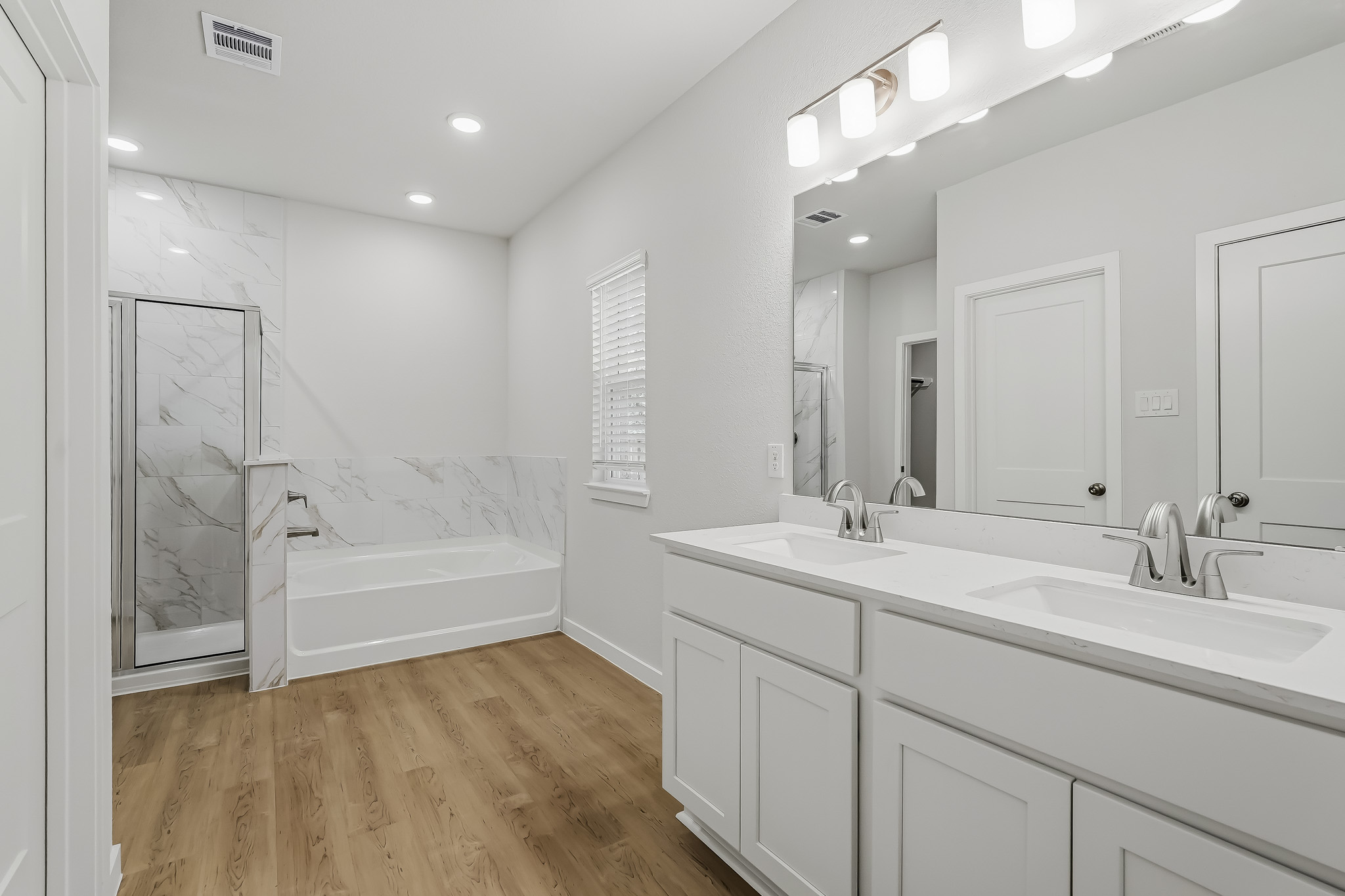 A bathroom with a tub sink and mirror.