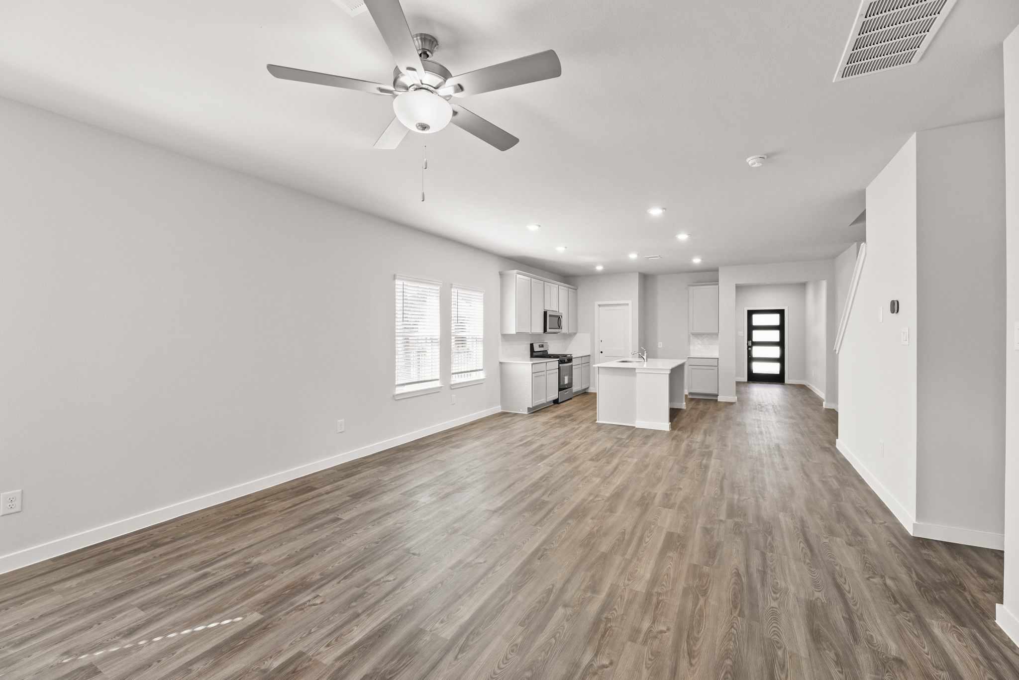A large empty room with a ceiling fan and a wood floor.