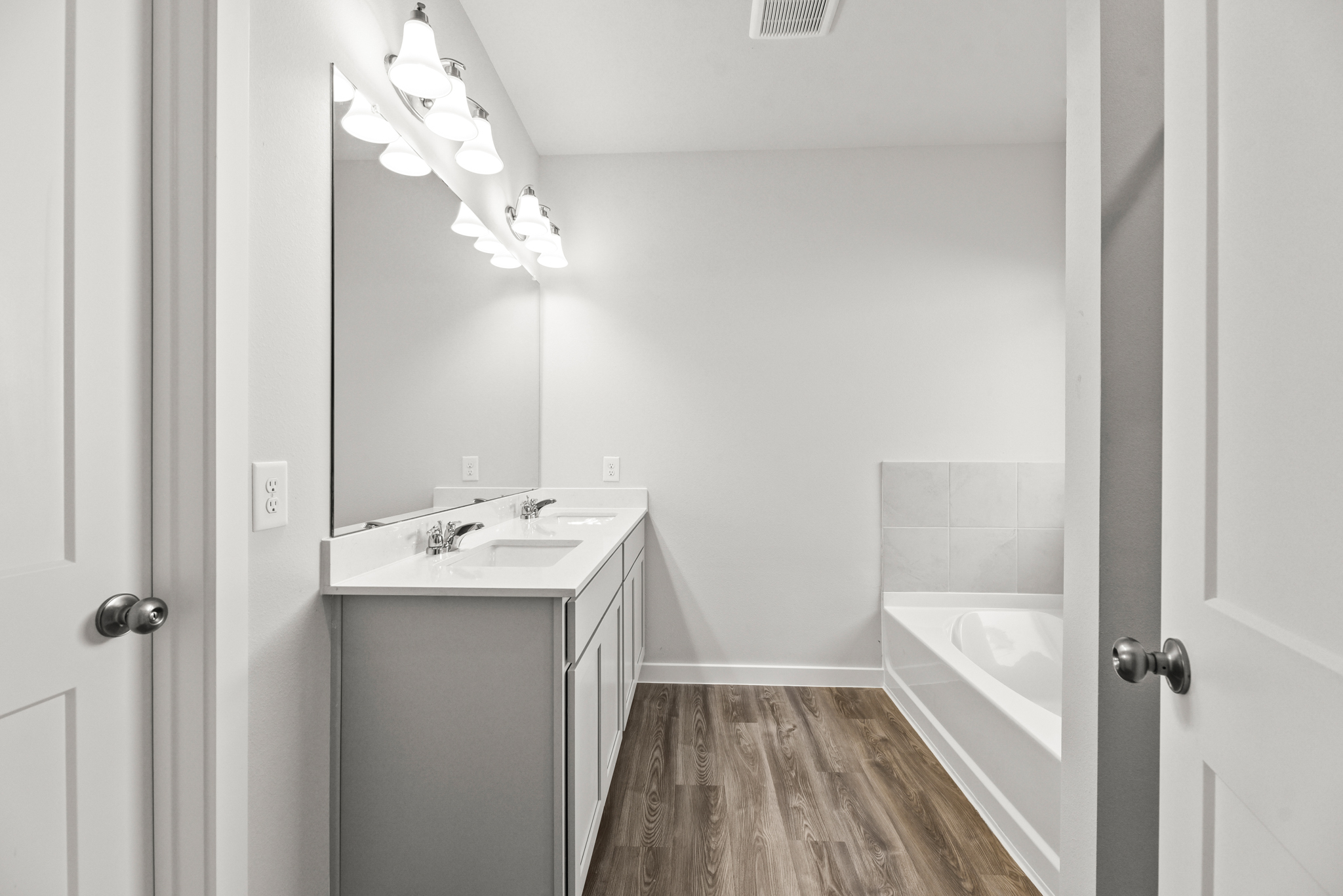 A bathroom with a tub sink and a mirror.