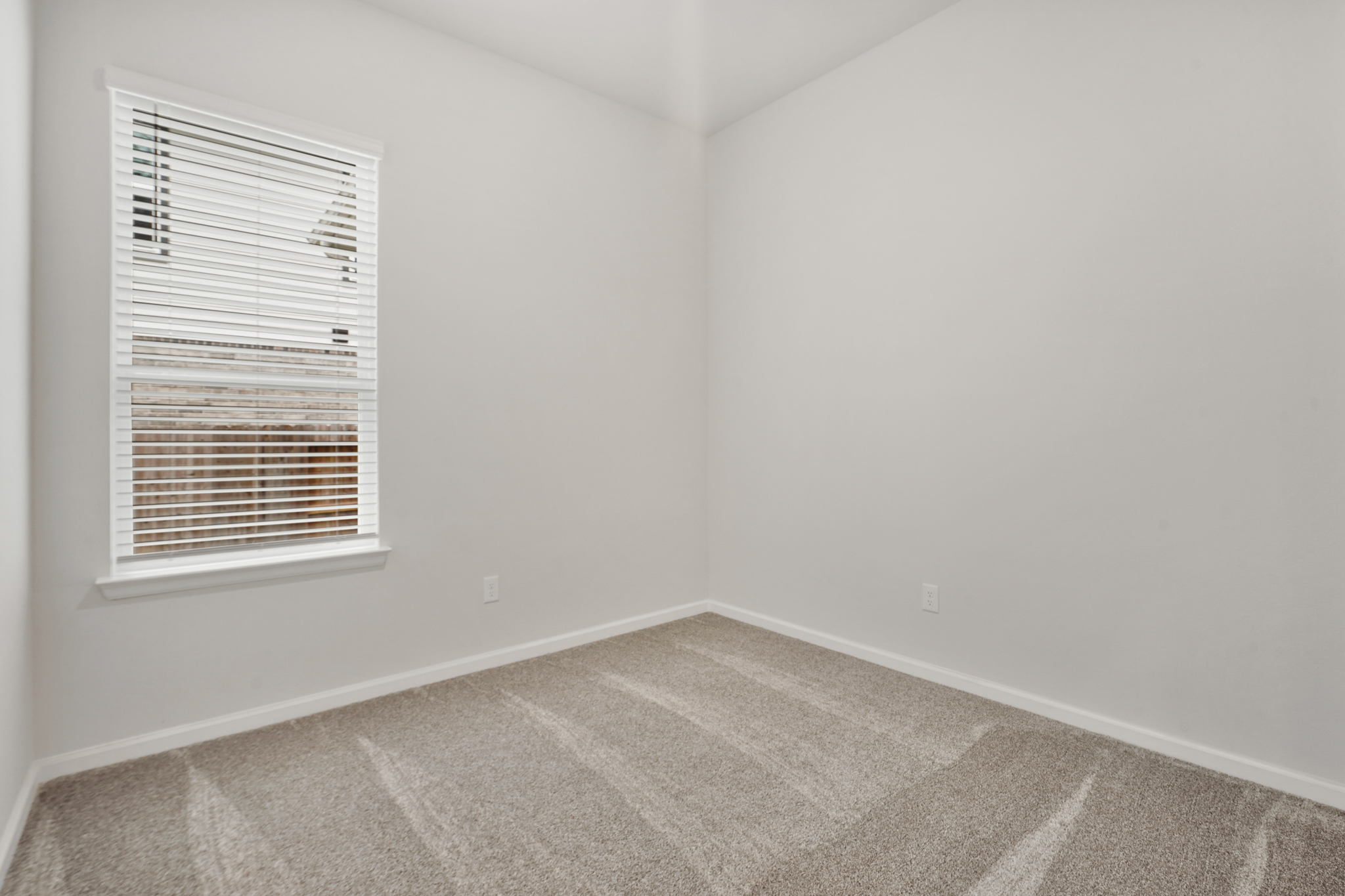 A room with a window and carpet.