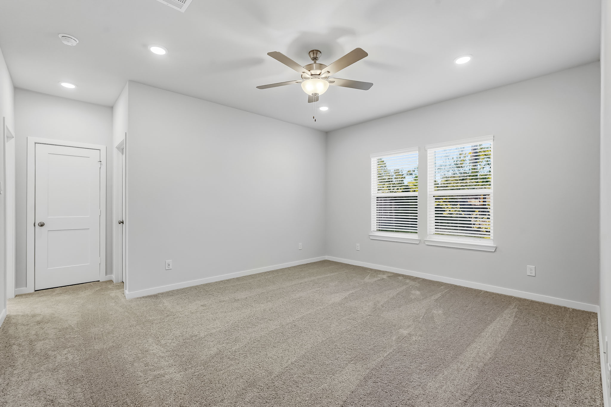 A room with a ceiling fan and a door.