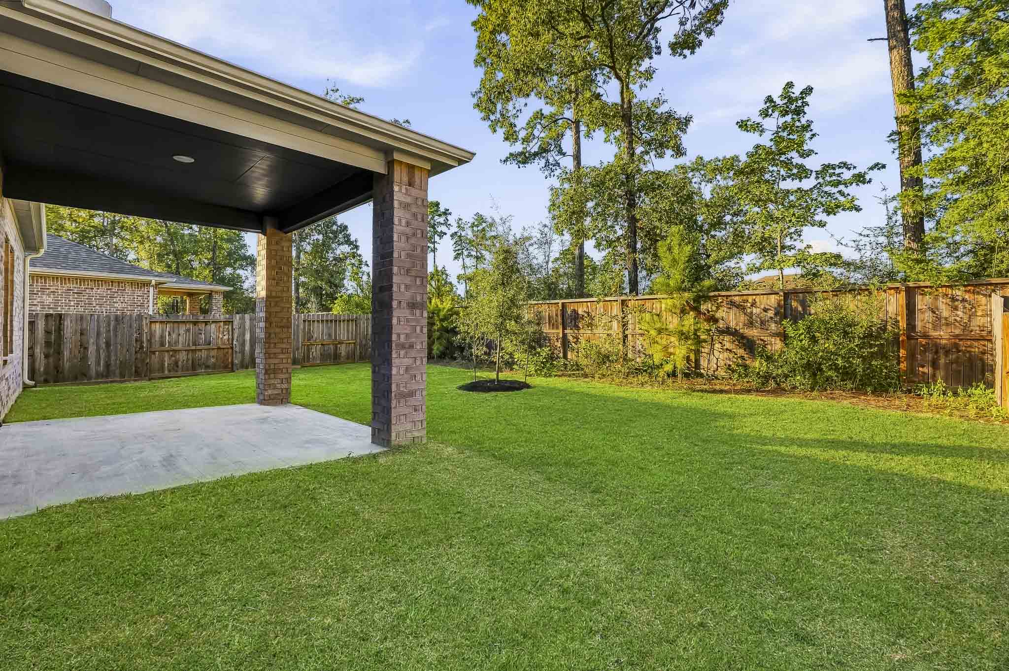 A backyard with a fence and a grass yard.