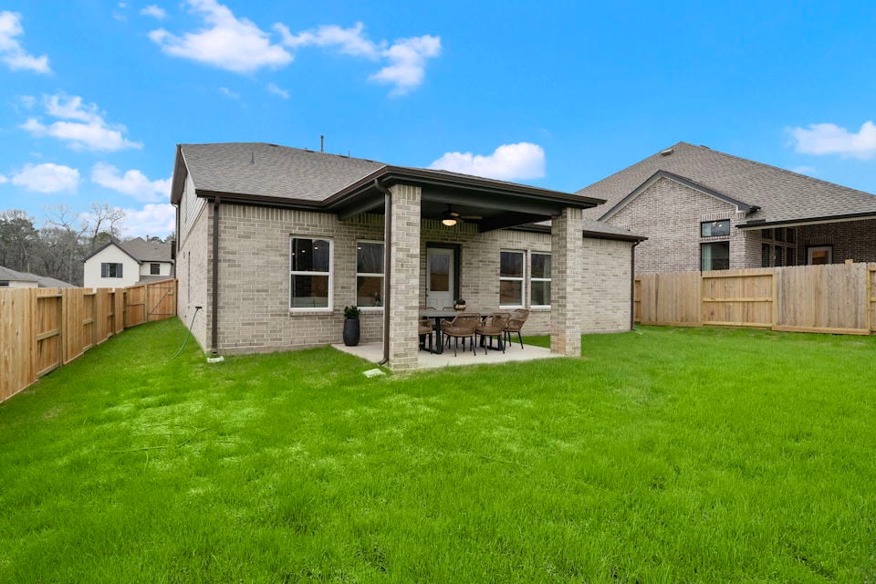 A house with a fence and a lawn in front of it.