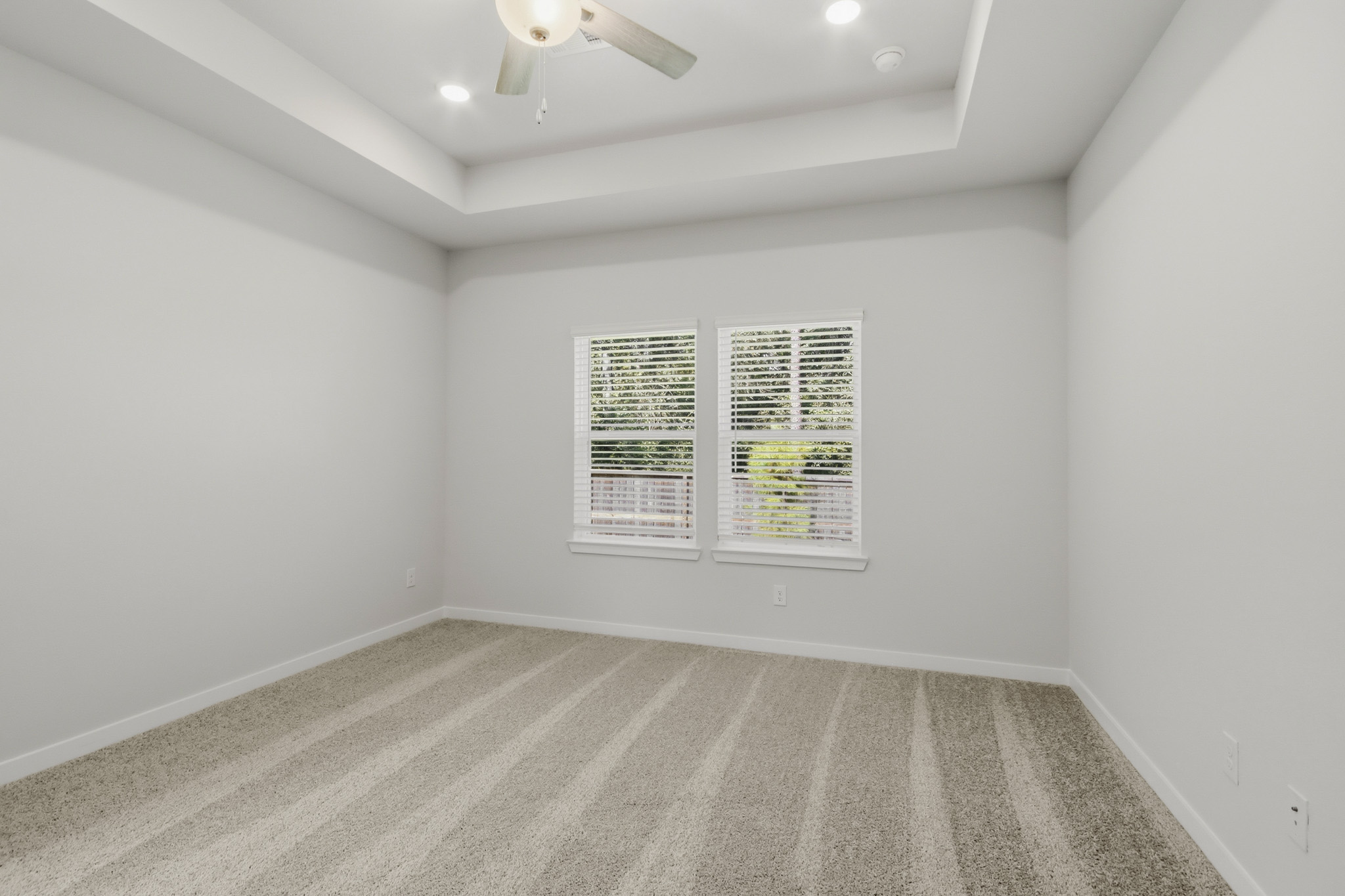 A room with a carpet and a ceiling fan.