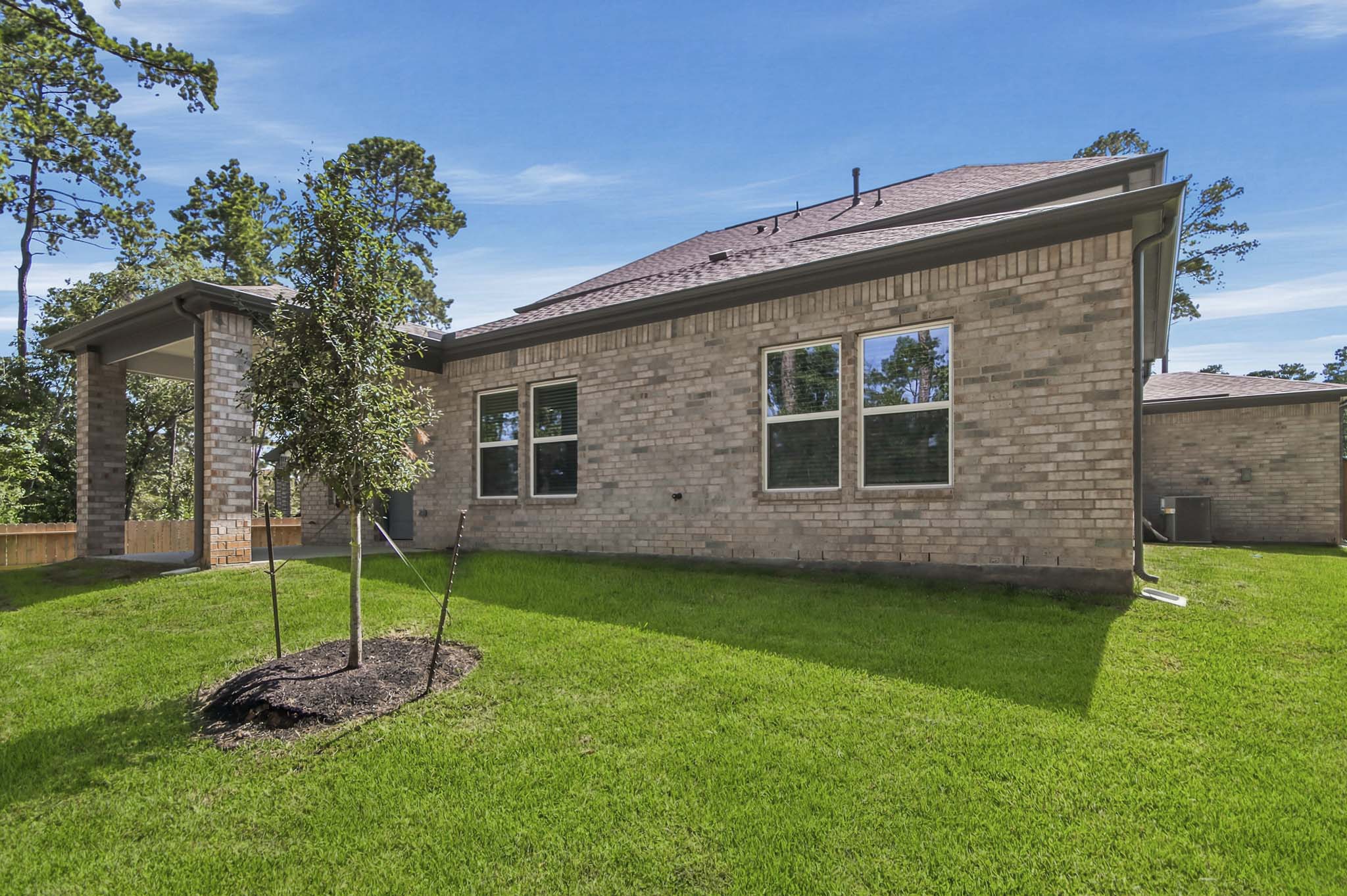 A brick house with a tree in the front yard.