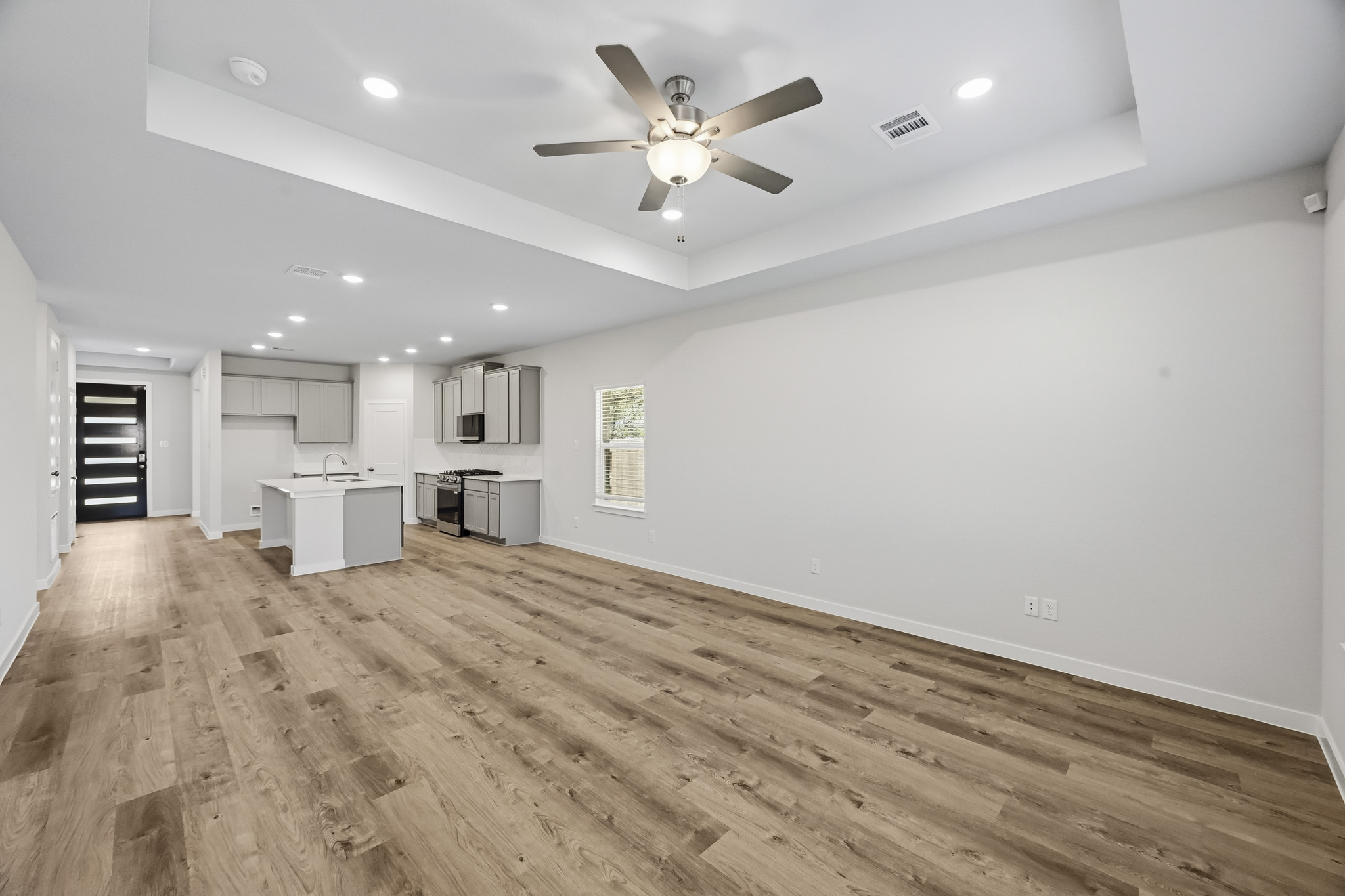 A large empty room with a wood floor and a ceiling fan.