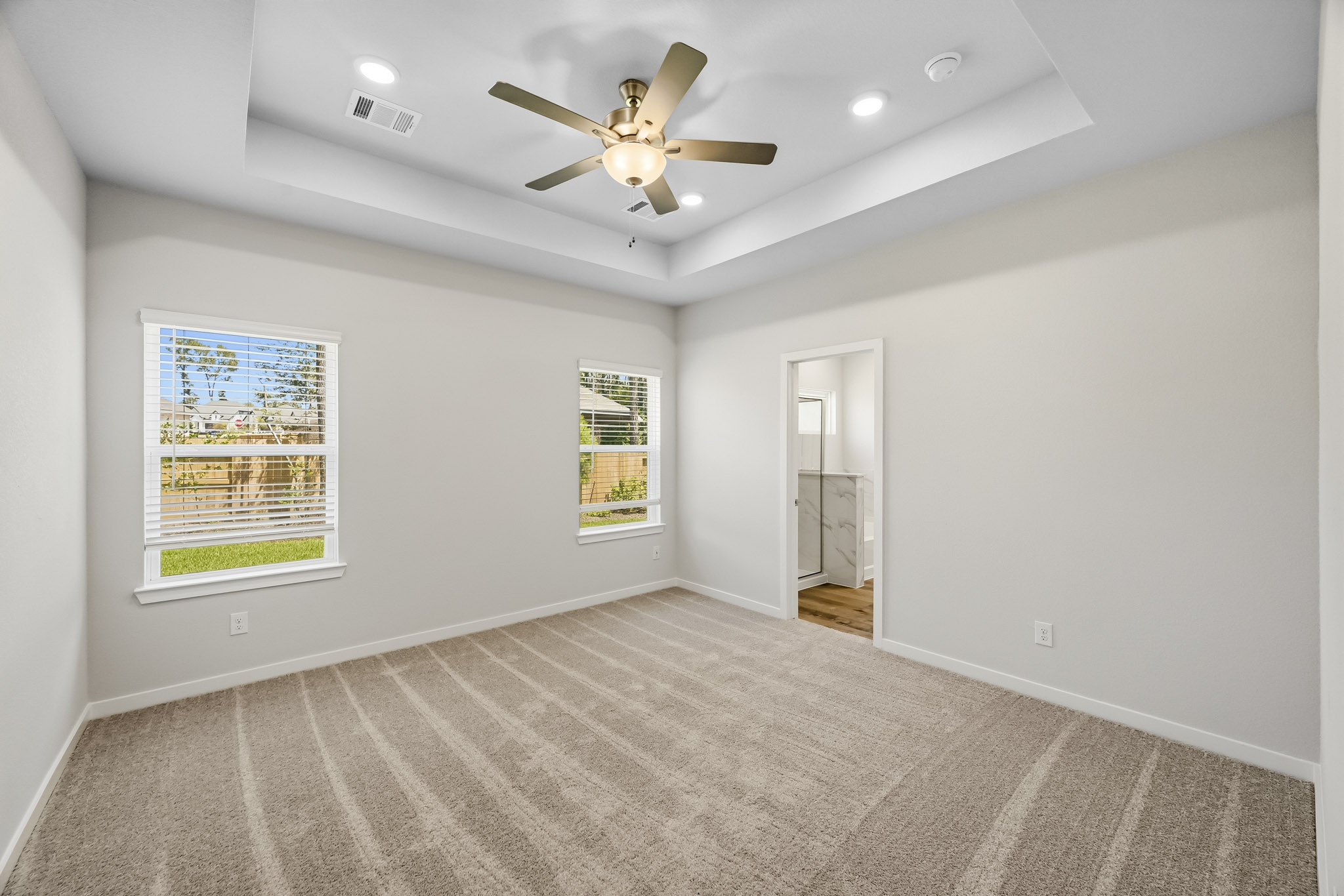 A large empty room with a ceiling fan and a large white carpet.