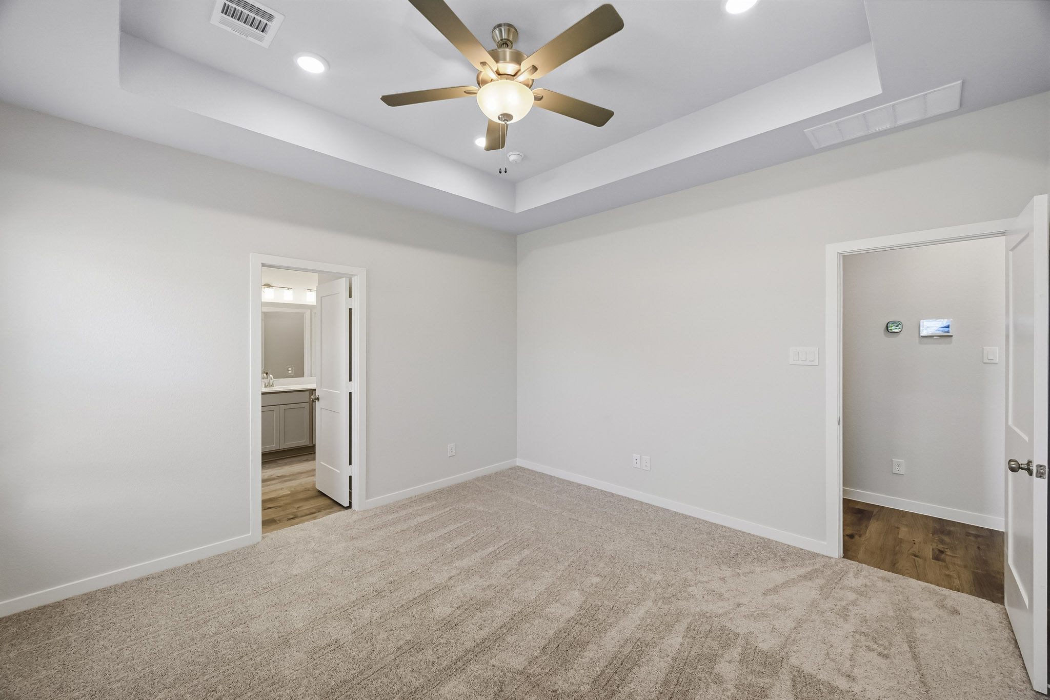 A room with a ceiling fan and a carpet.