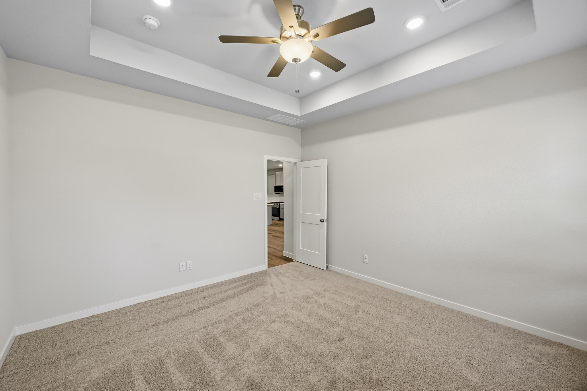 A room with a ceiling fan and a carpet.