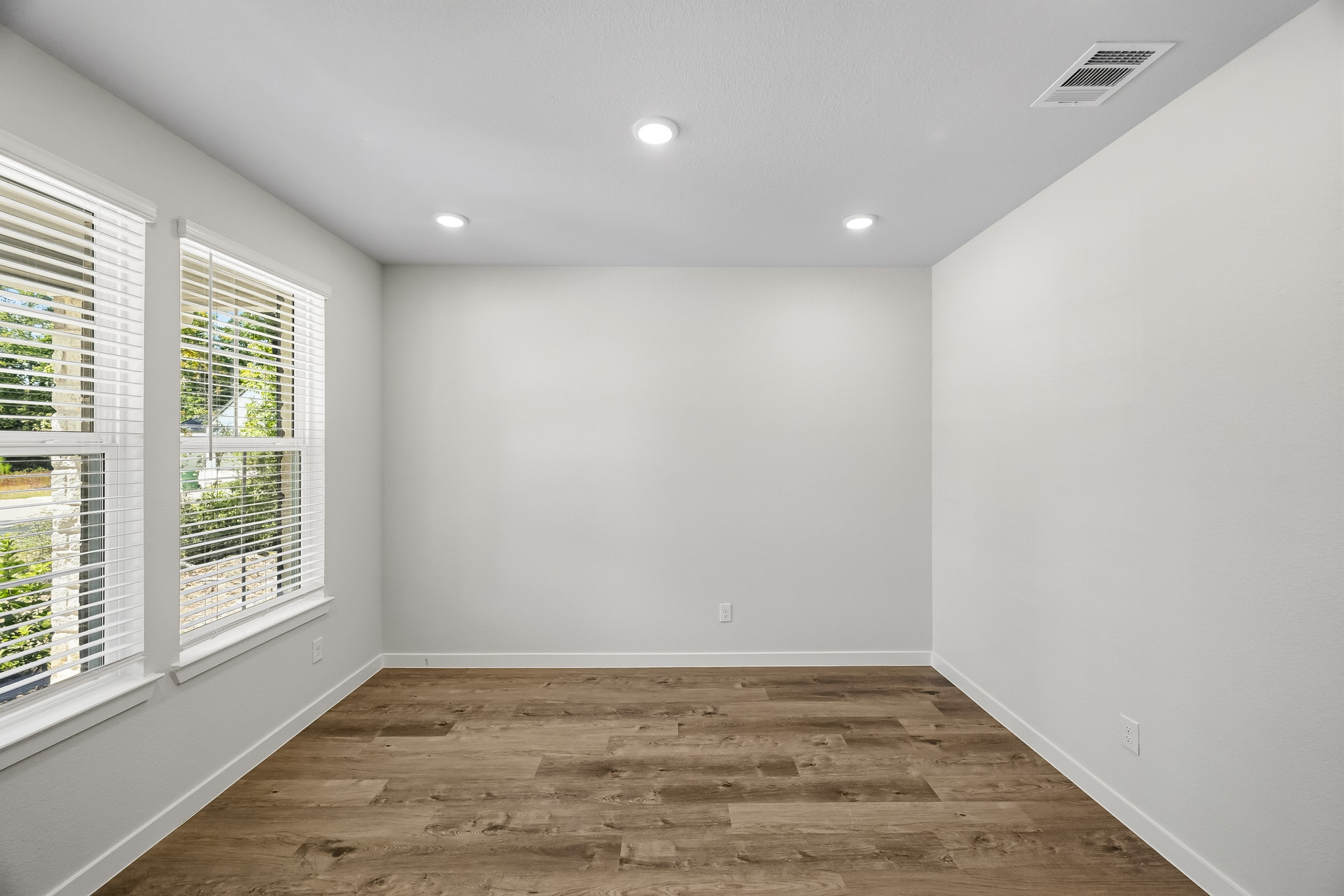 A room with a wood floor and windows.