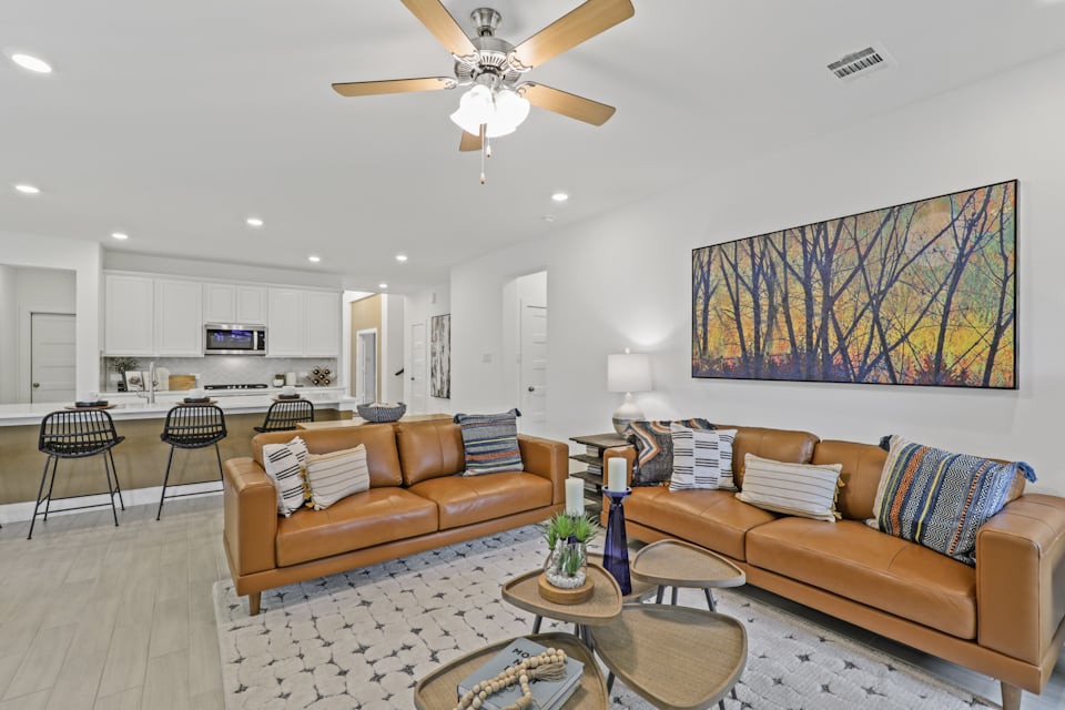 A living room with a couch and a fan.