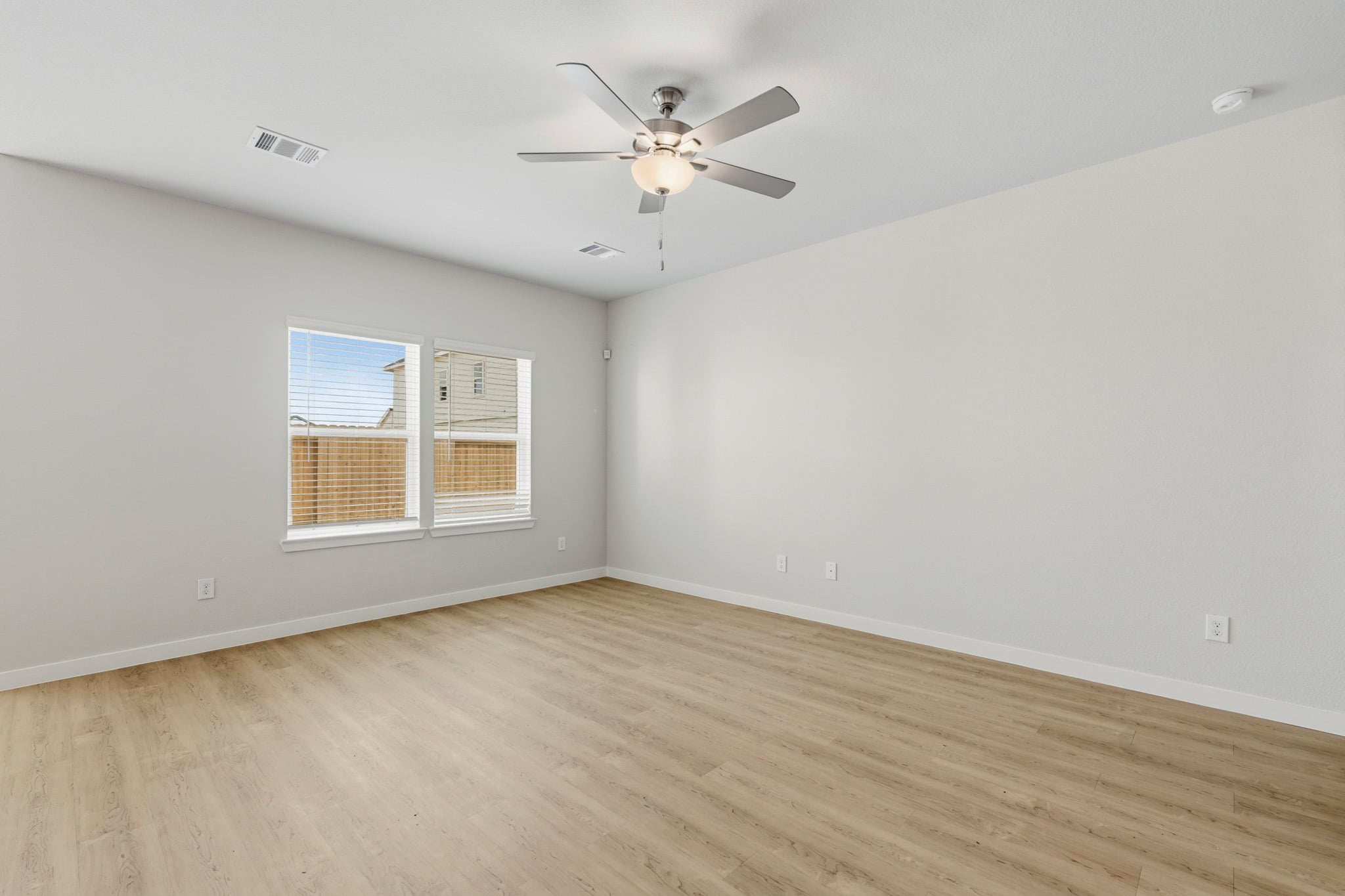 A room with a ceiling fan and a wood floor.