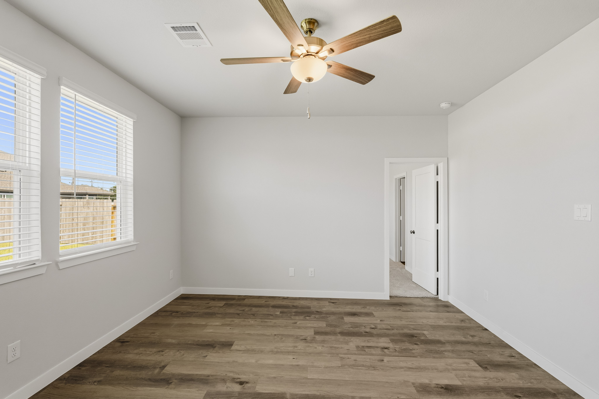 A room with a ceiling fan and windows.