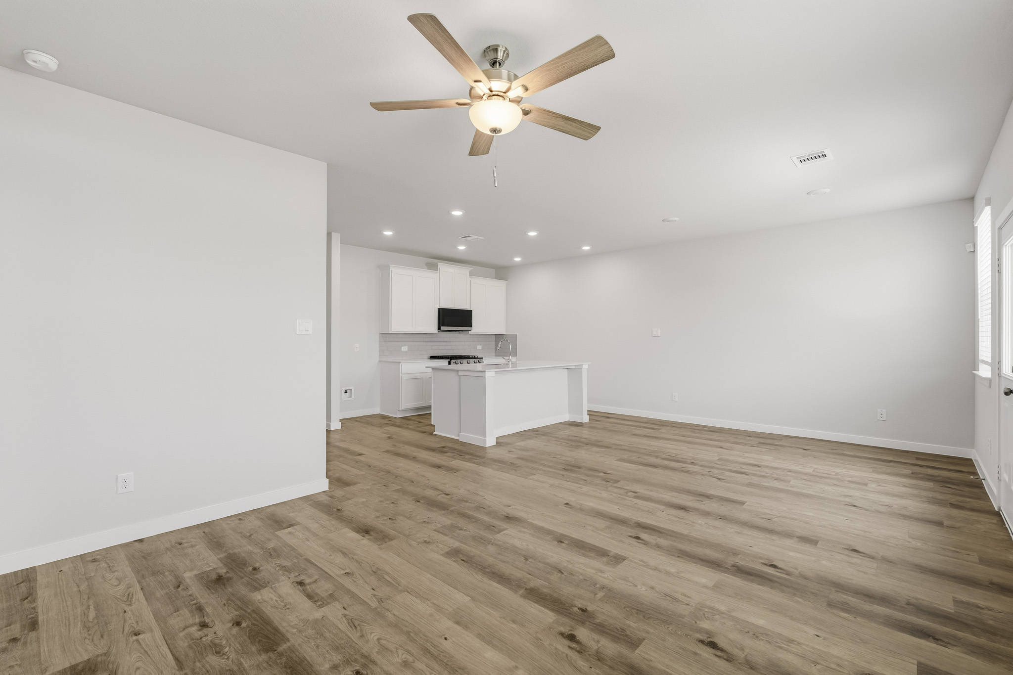 A room with a wood floor and a ceiling fan.
