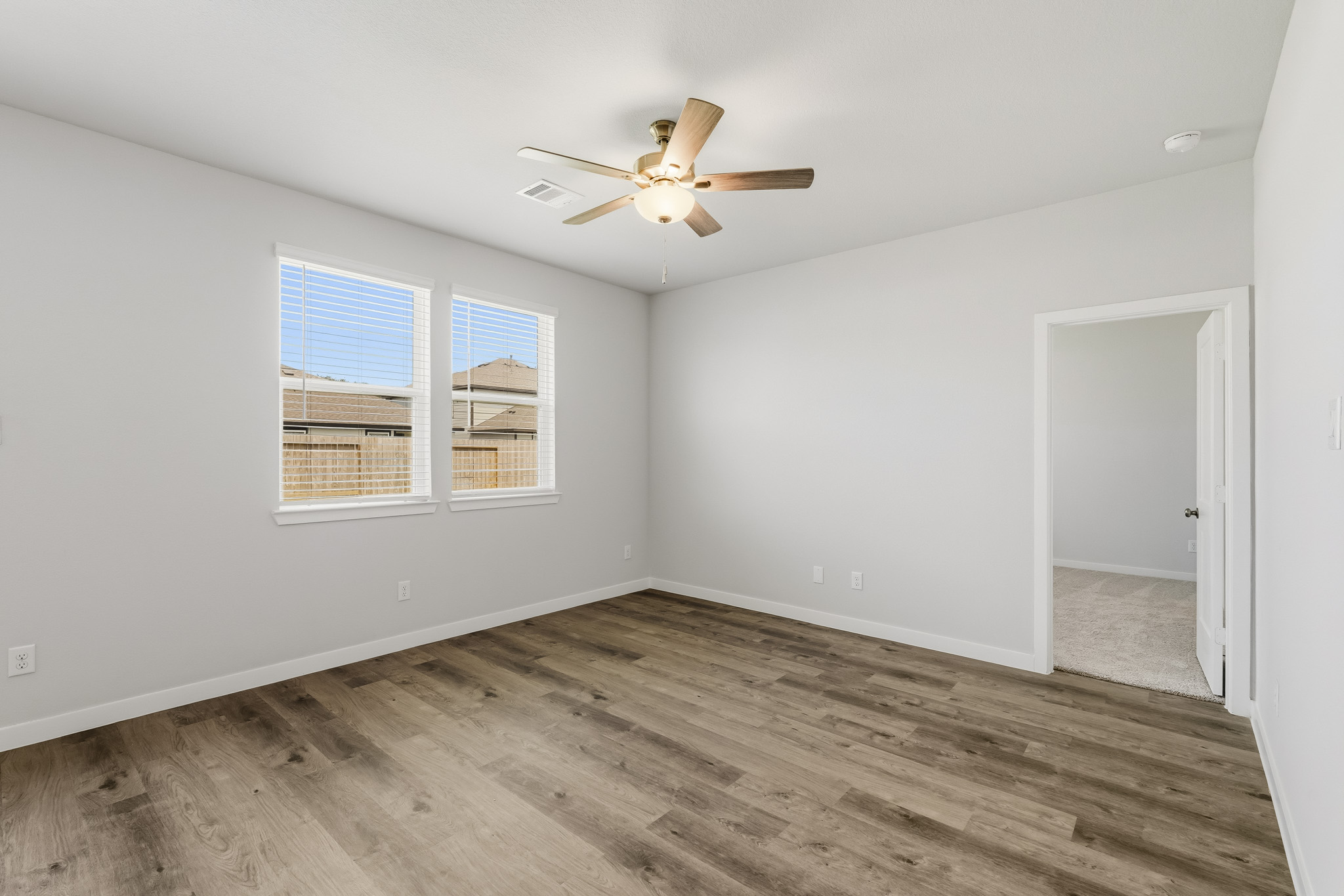 A room with a ceiling fan and a wood floor.