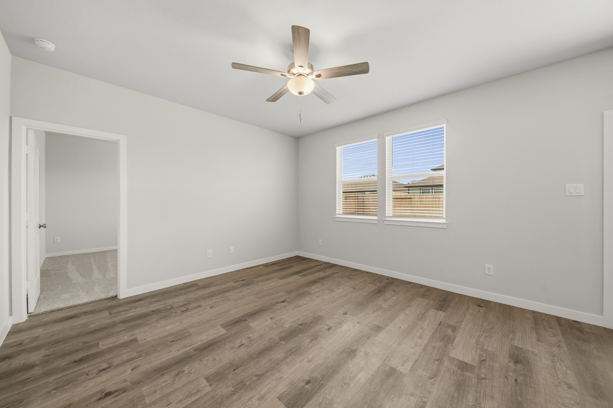 A room with a ceiling fan and a wood floor.