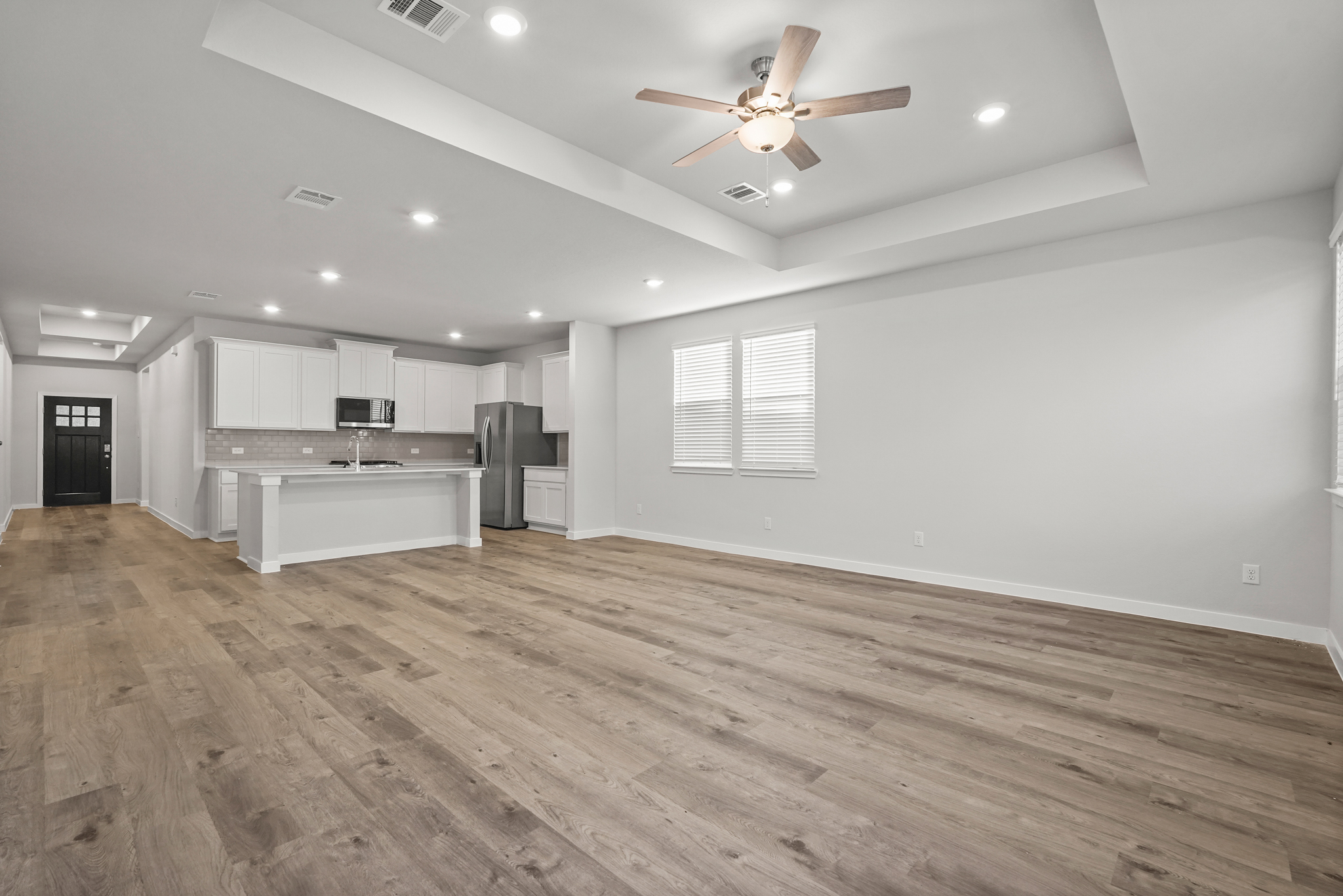 A large empty room with a wood floor and a ceiling fan.