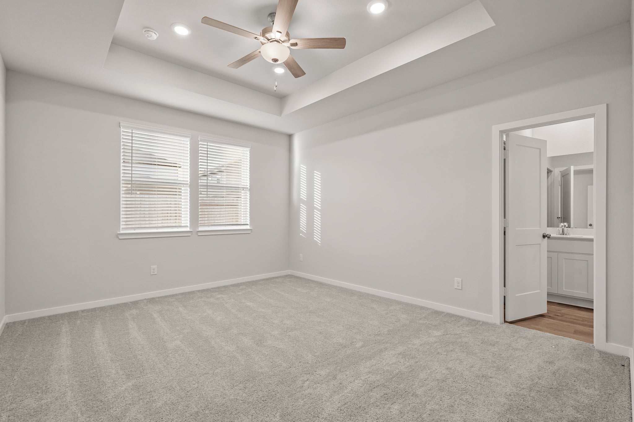 A large room with a ceiling fan and a door.