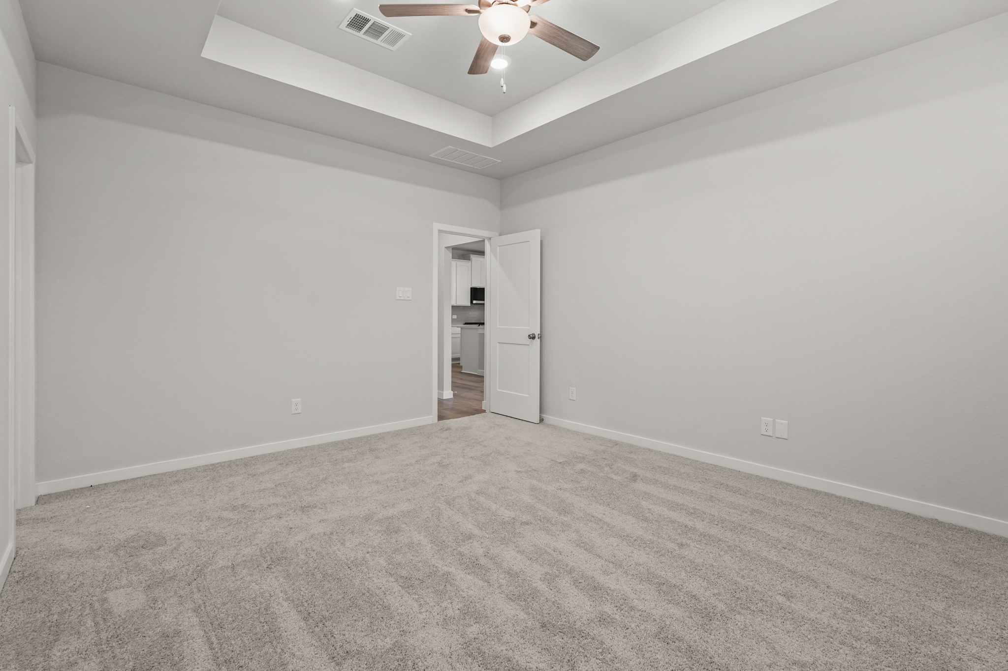 A room with a ceiling fan and a carpet.