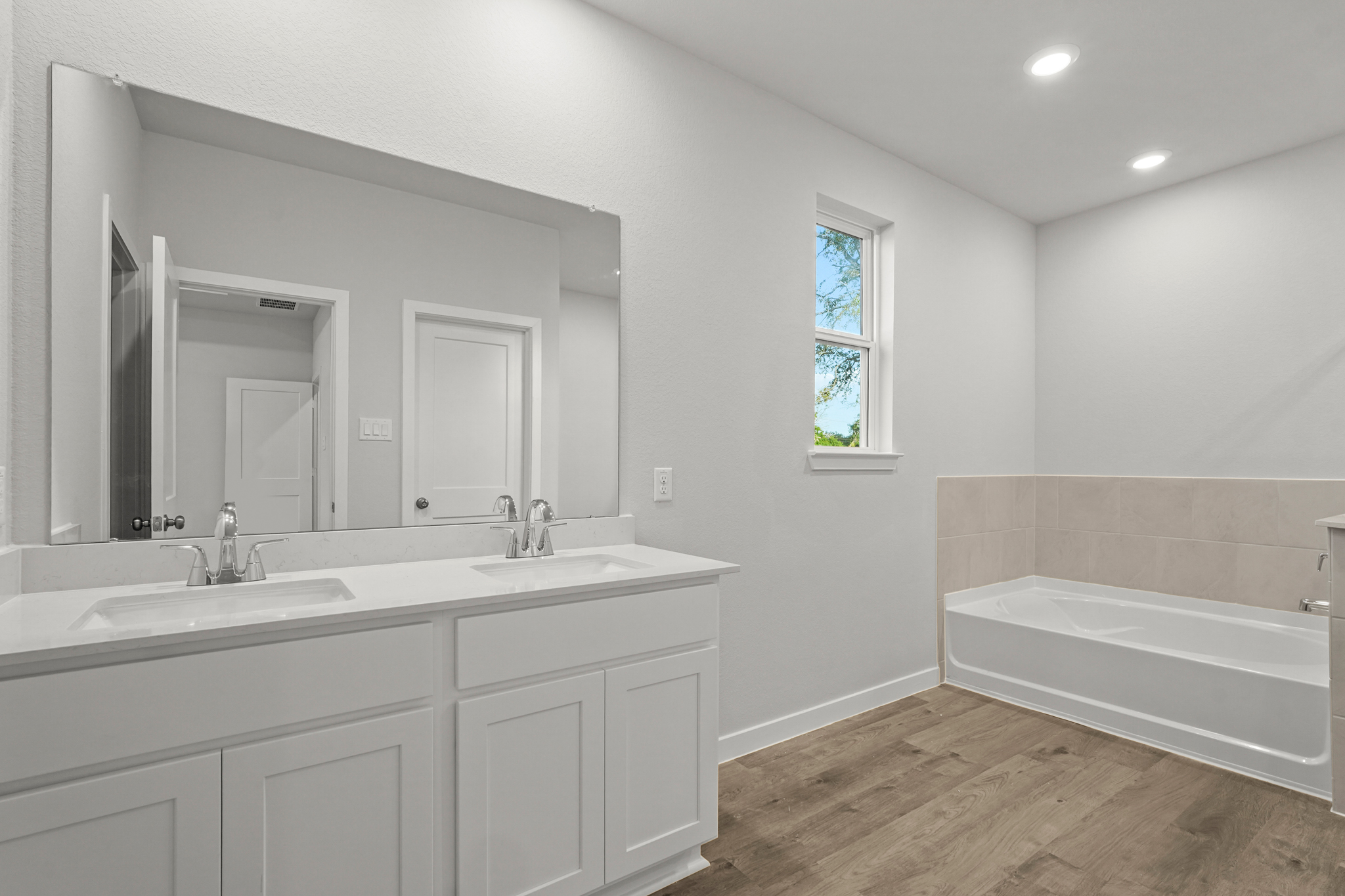 A bathroom with a tub sink and a mirror.