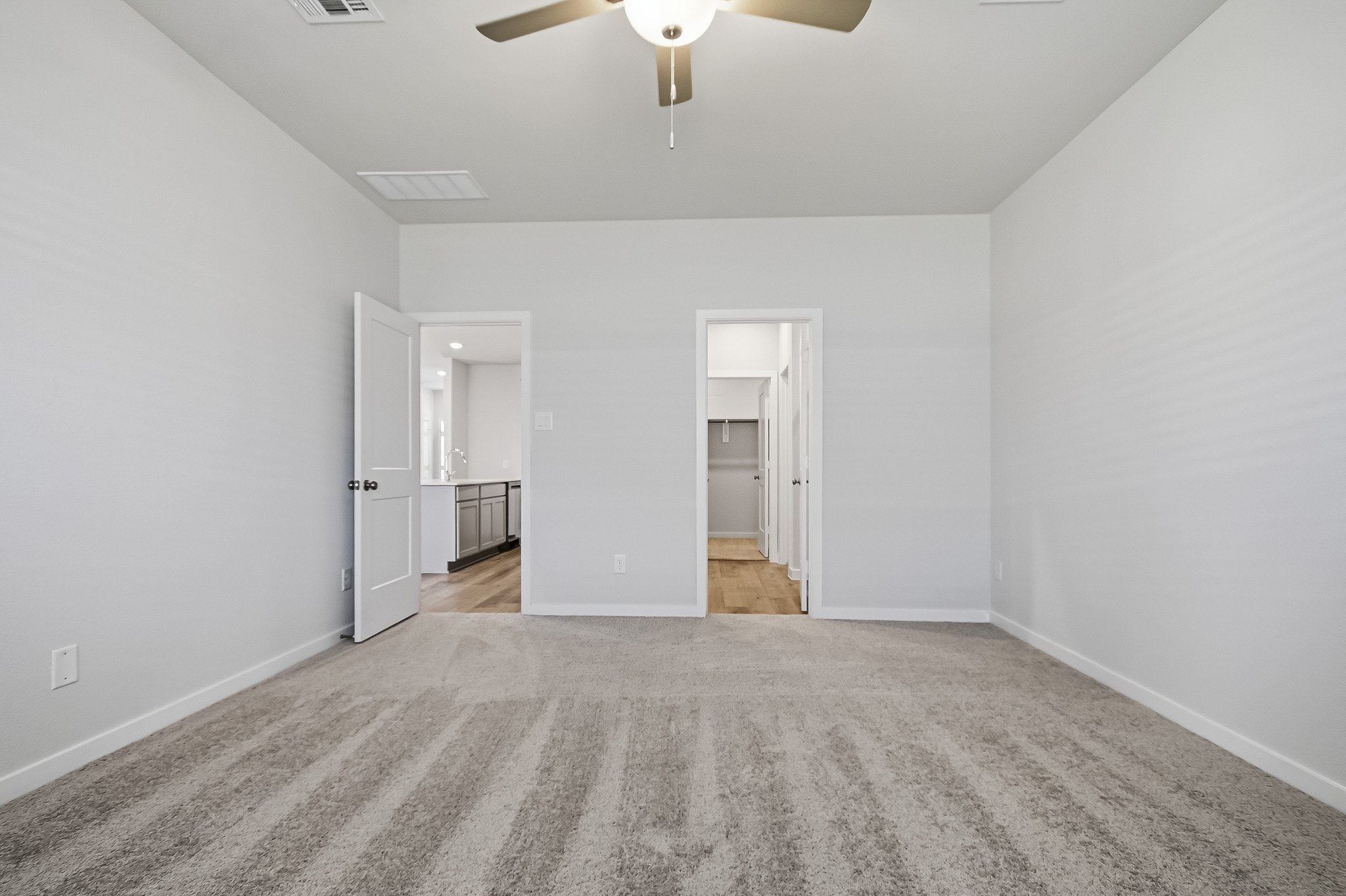 A room with a ceiling fan and a door.