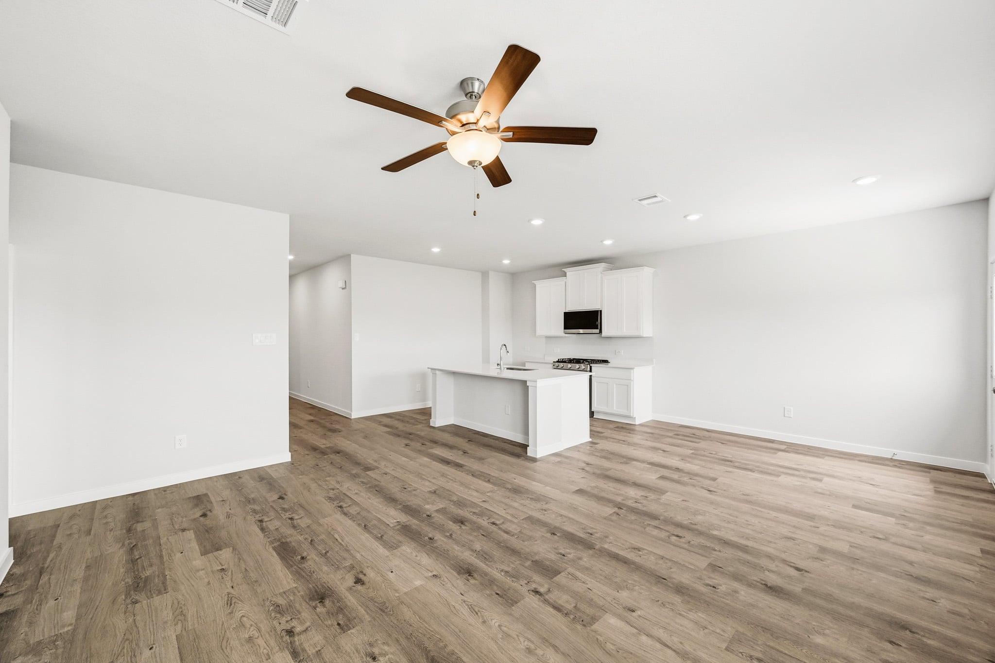 A room with a wood floor and a ceiling fan.