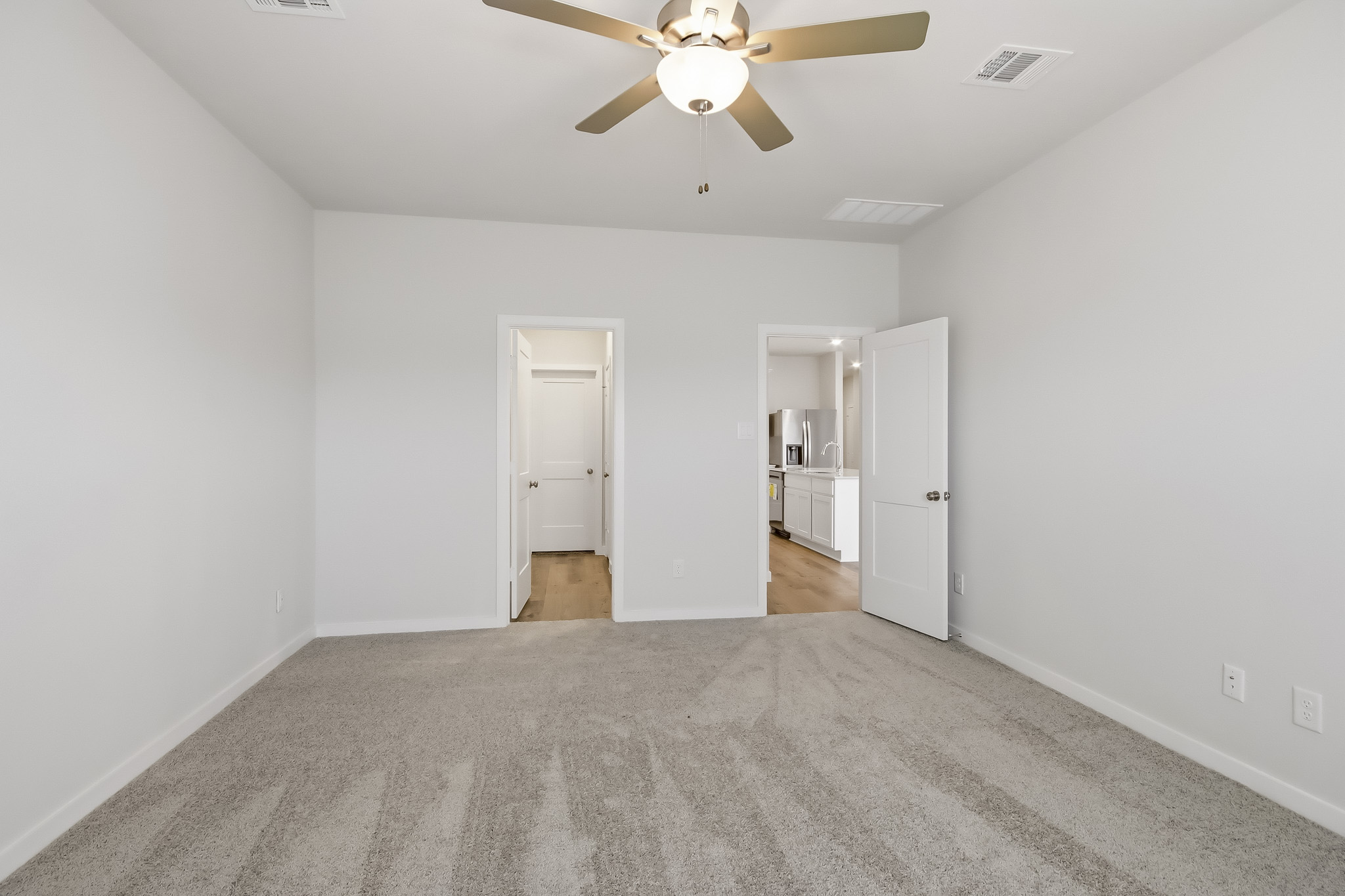 A room with a ceiling fan and a door.