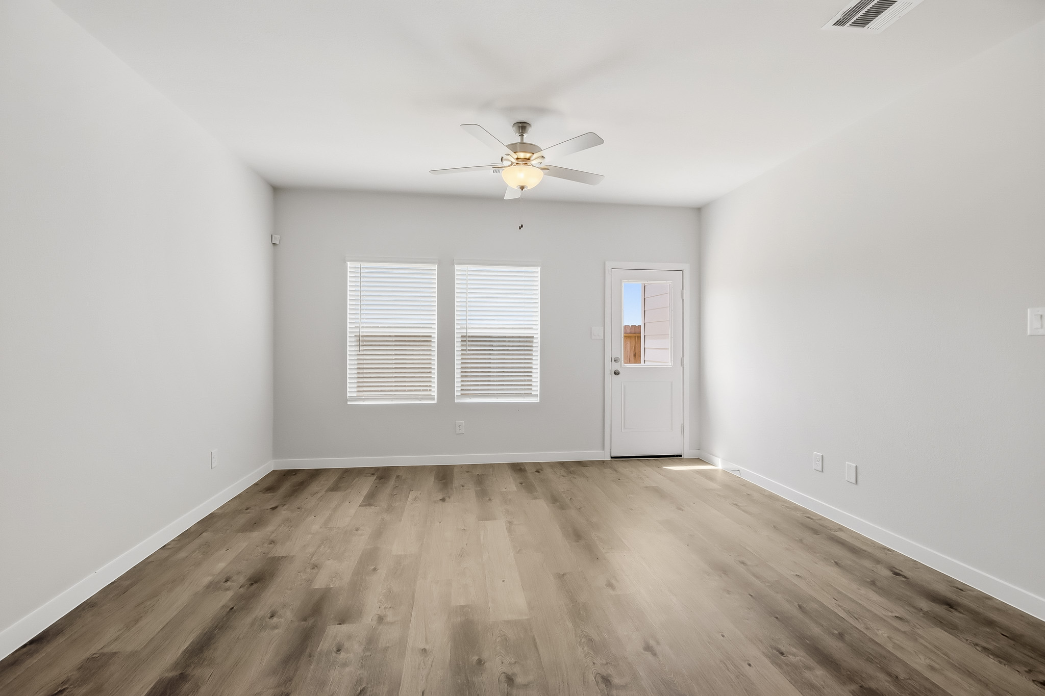 A room with a ceiling fan and a wood floor.
