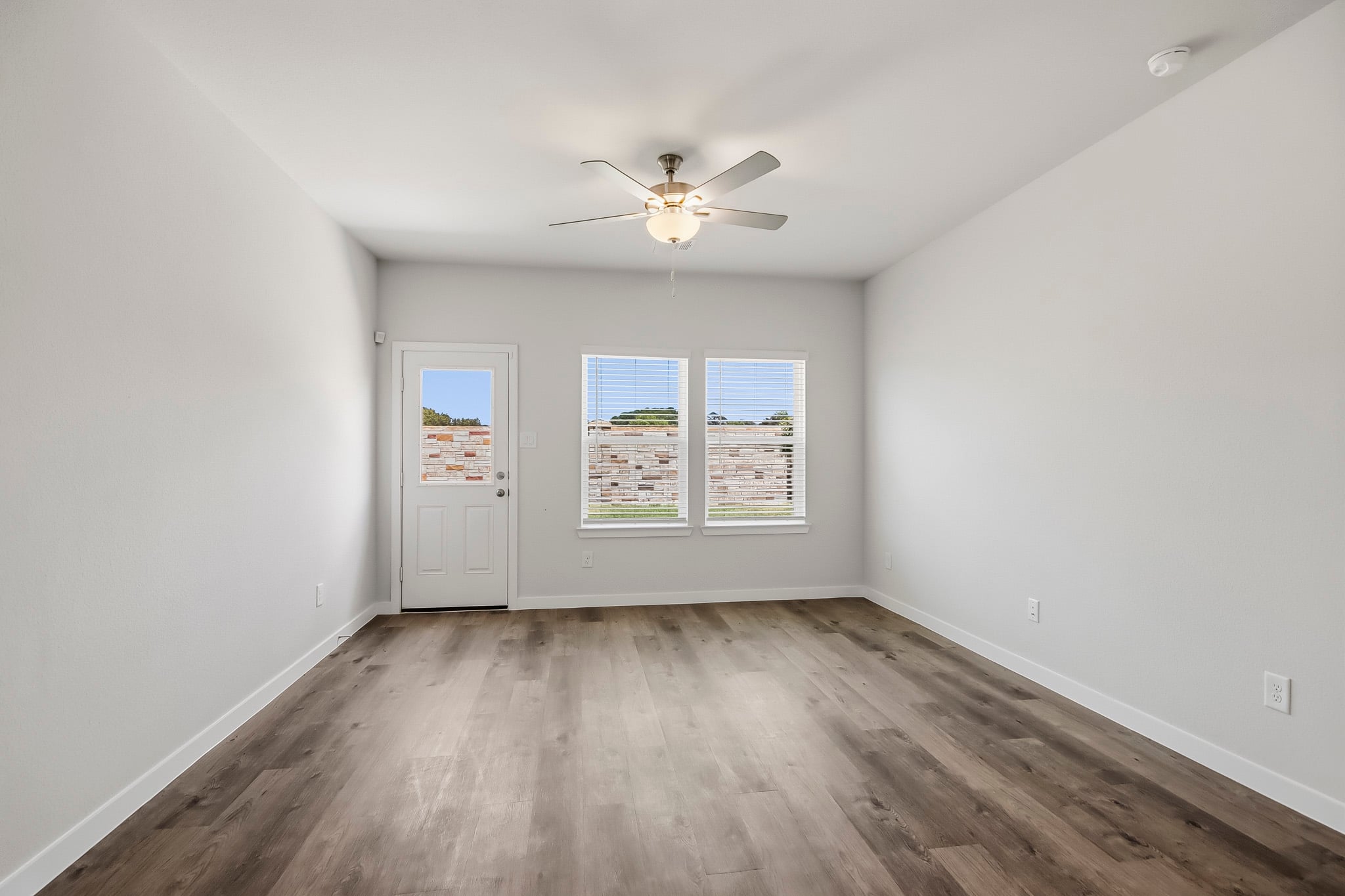 A room with a ceiling fan and a wood floor.