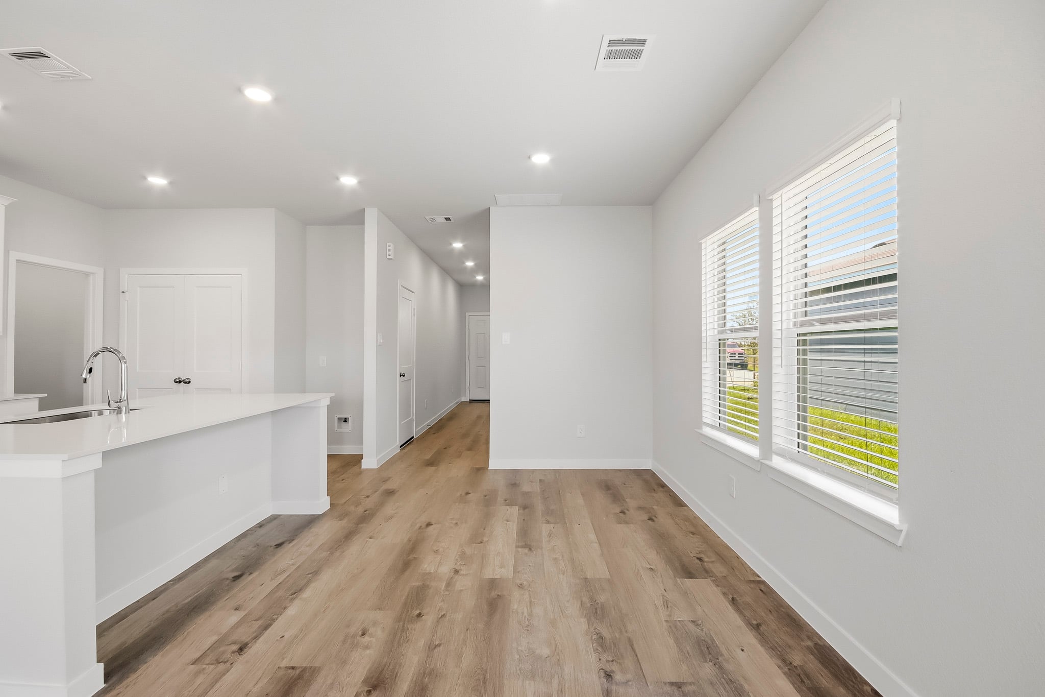 A large white kitchen with a wood floor.