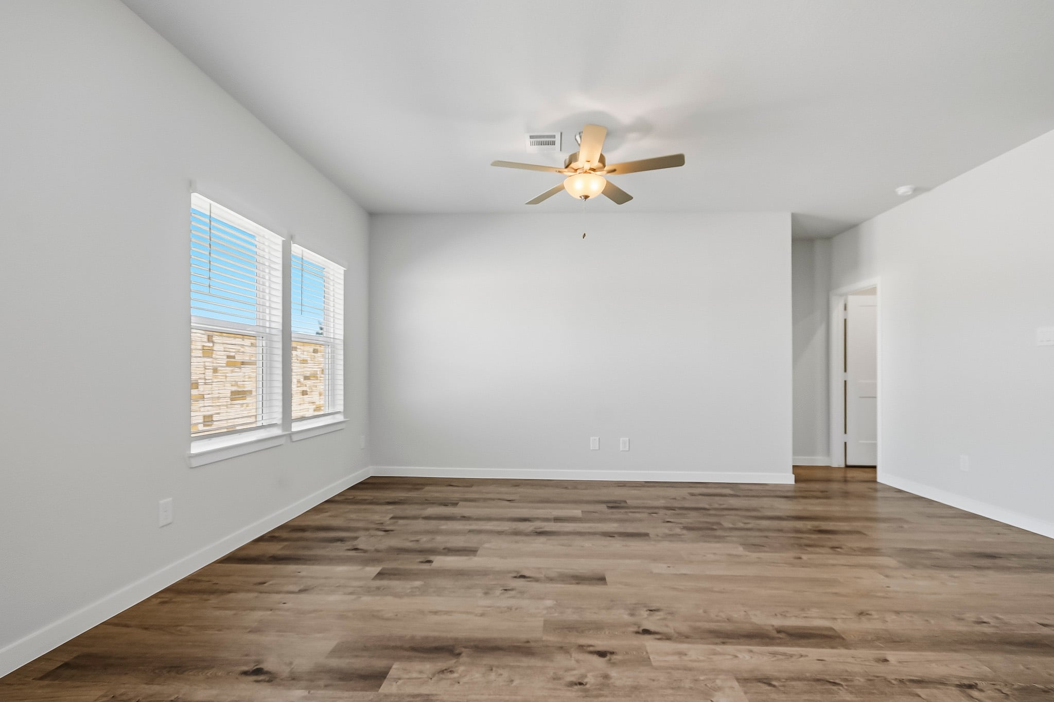 A room with a ceiling fan and a wood floor.