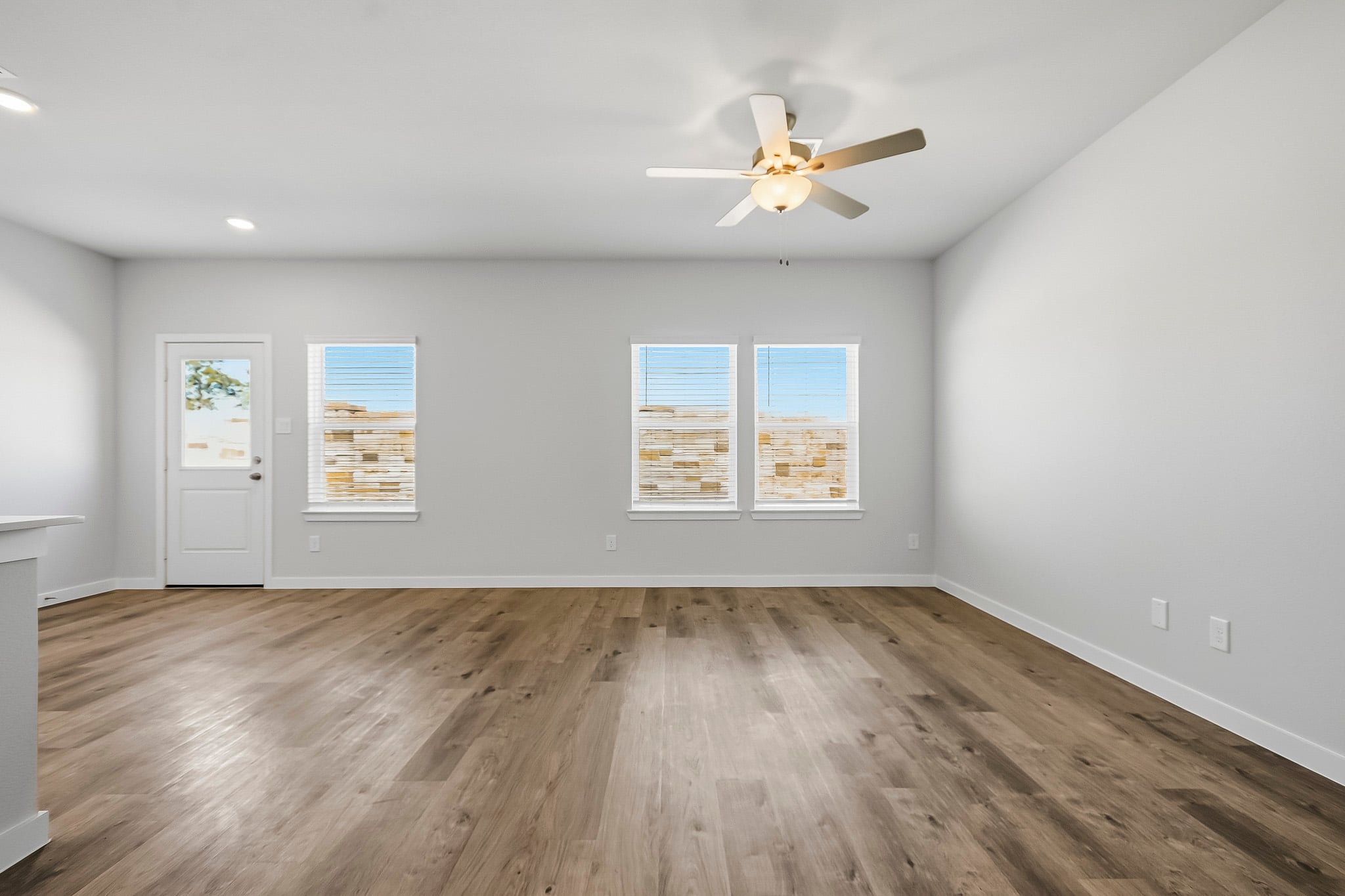 A room with a ceiling fan and a wood floor.