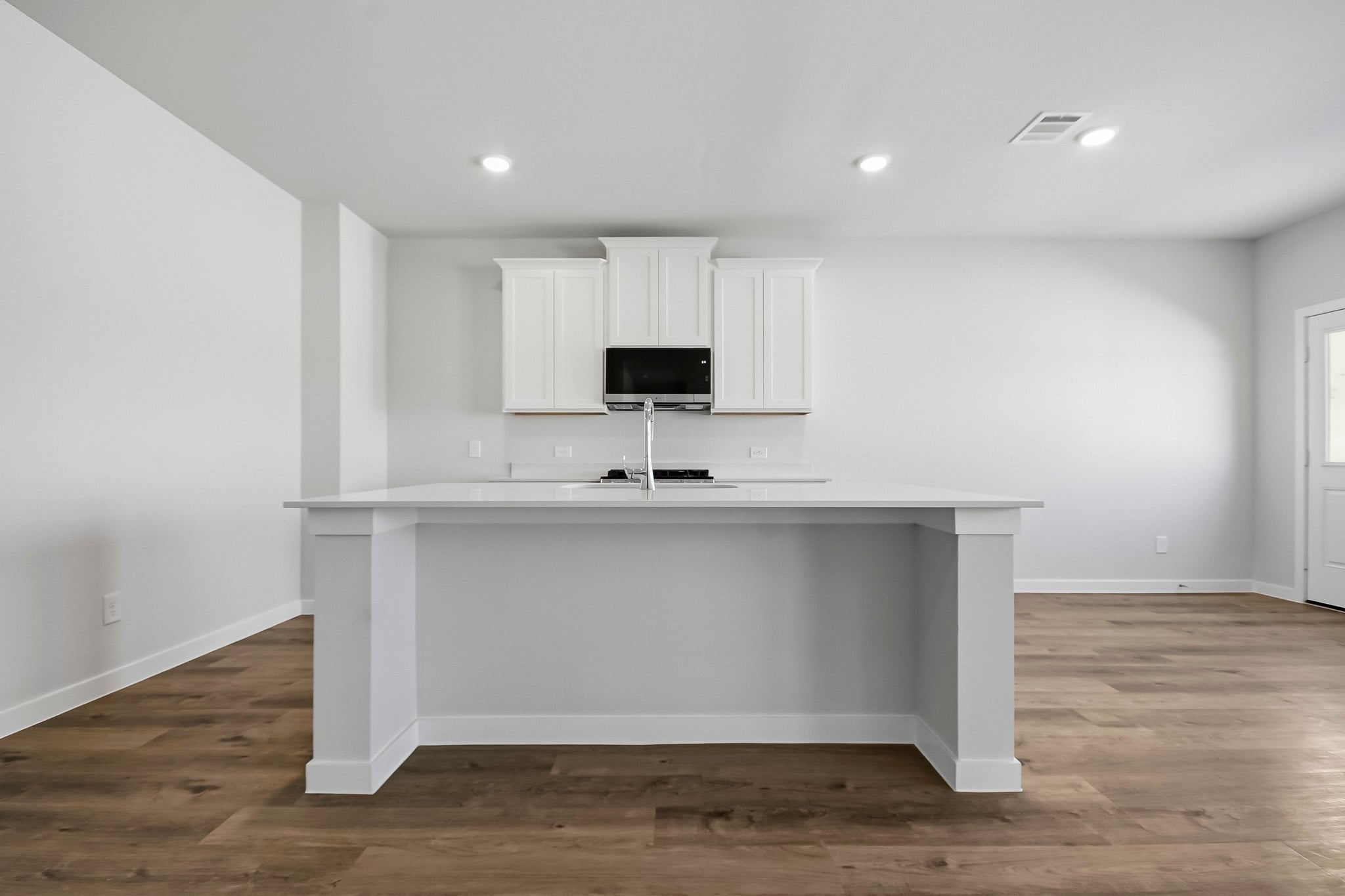 A white kitchen with a tv on a white counter.